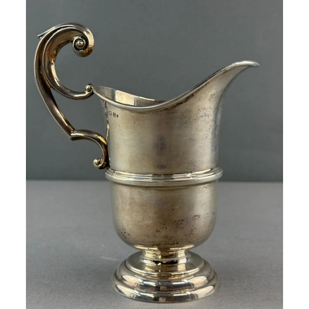 Silver: a cream jug of helmet form with bifurcated flying sc...
