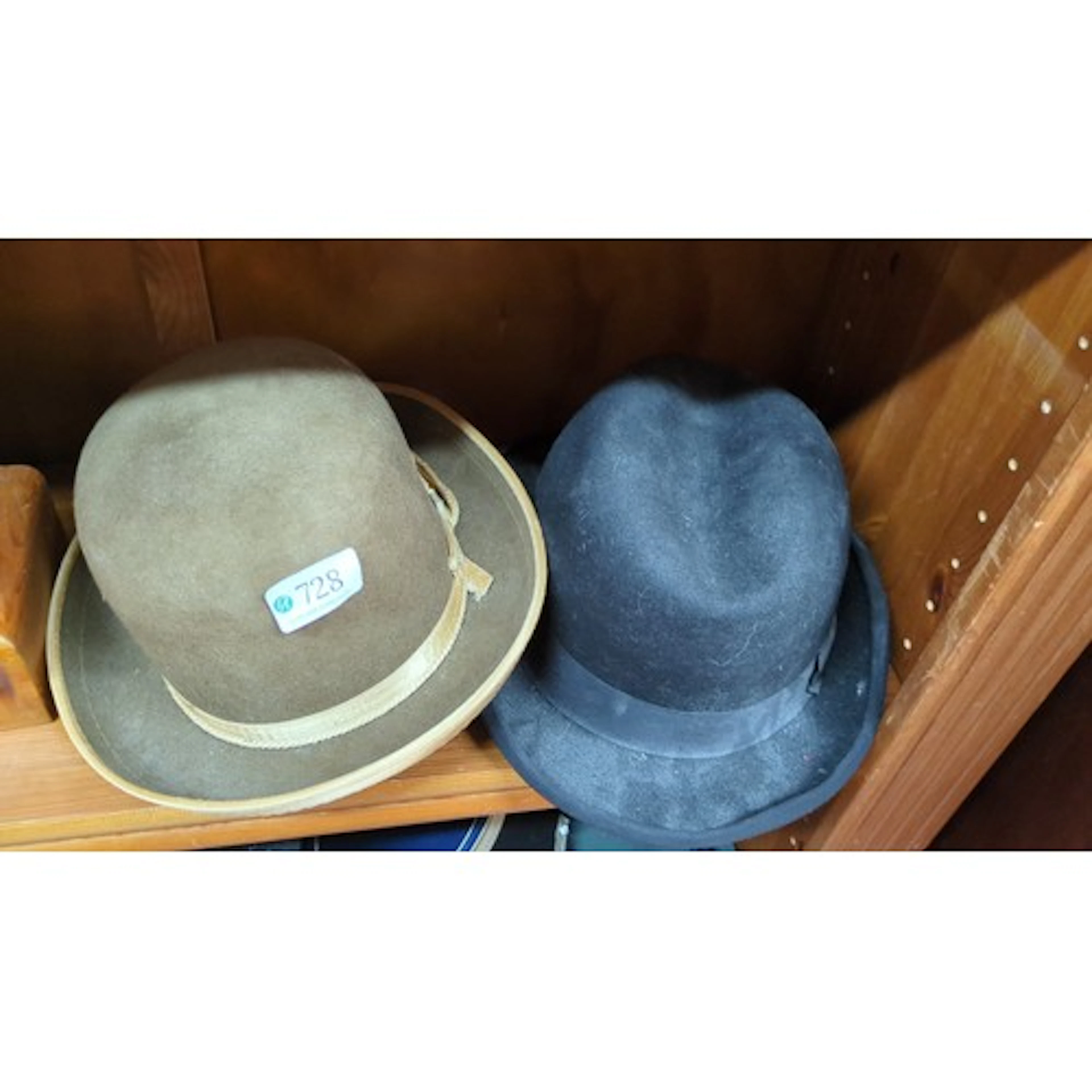 A pair of felt hats comprising a black trilby with grosgrain...