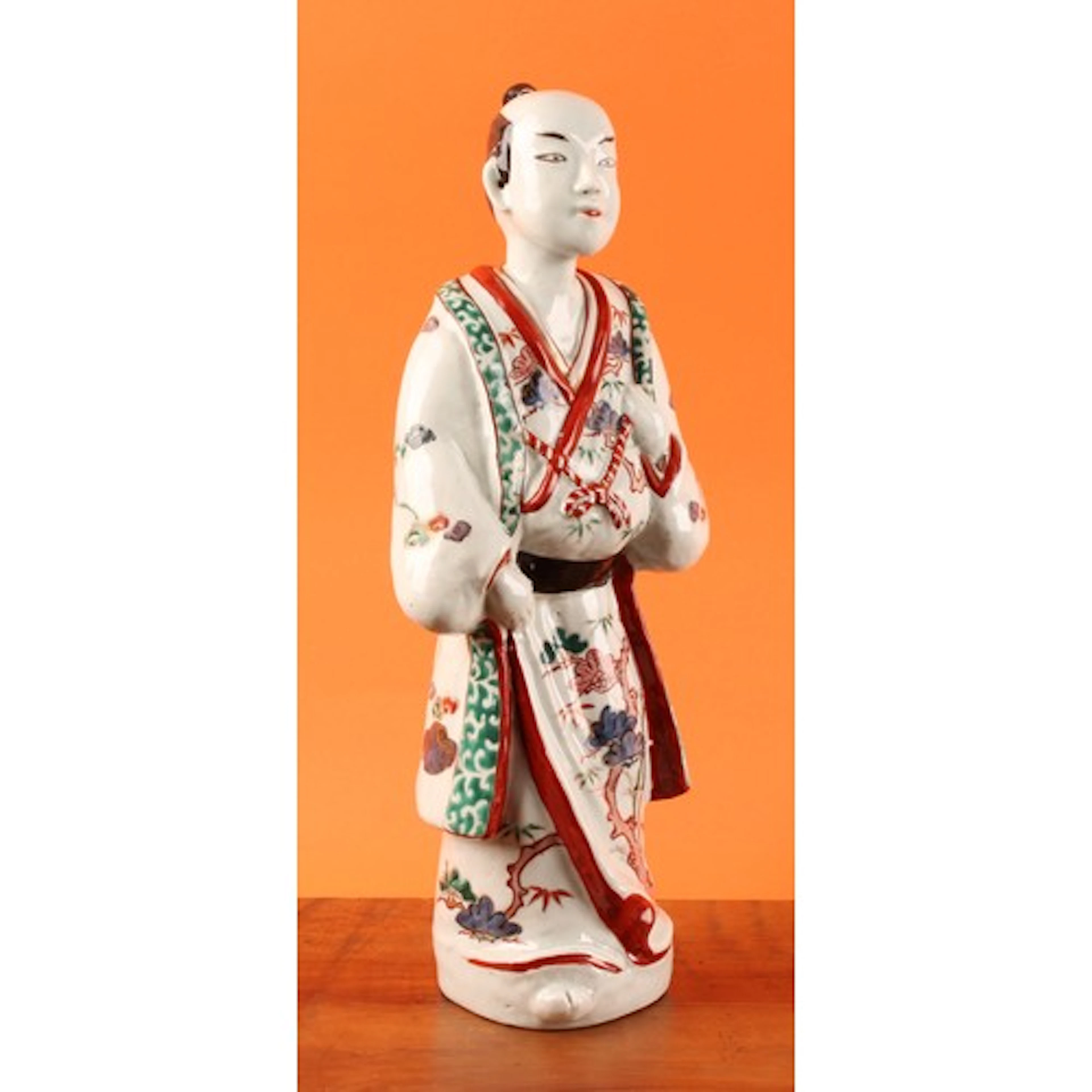 A Japanese kakiemon porcelain figure, of a man wearing a kim...