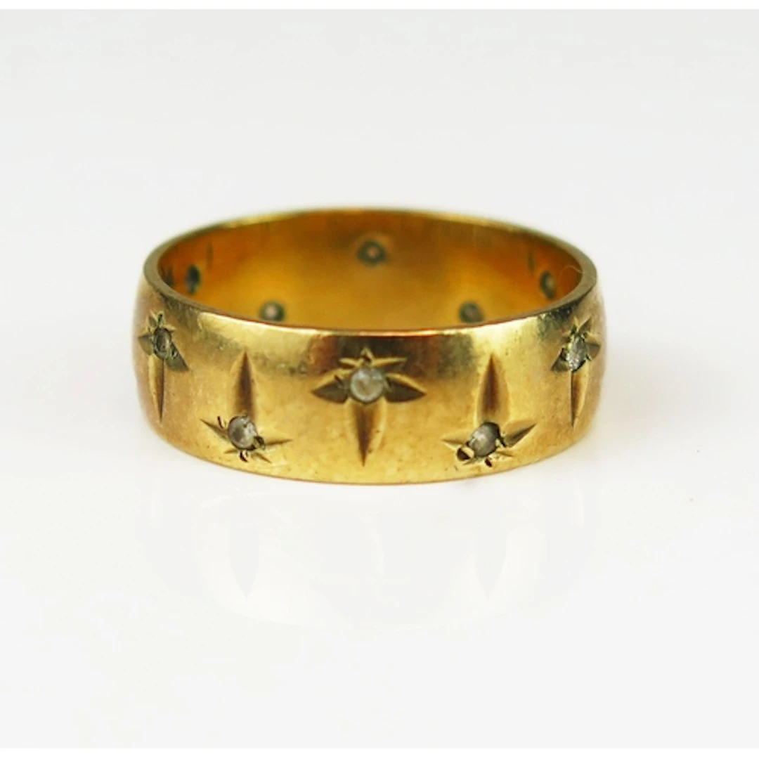 A 9ct yellow gold band set with white gems and chased foliat...