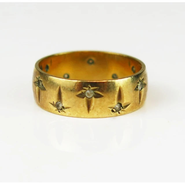A 9ct yellow gold band set with white gems and chased foliat...