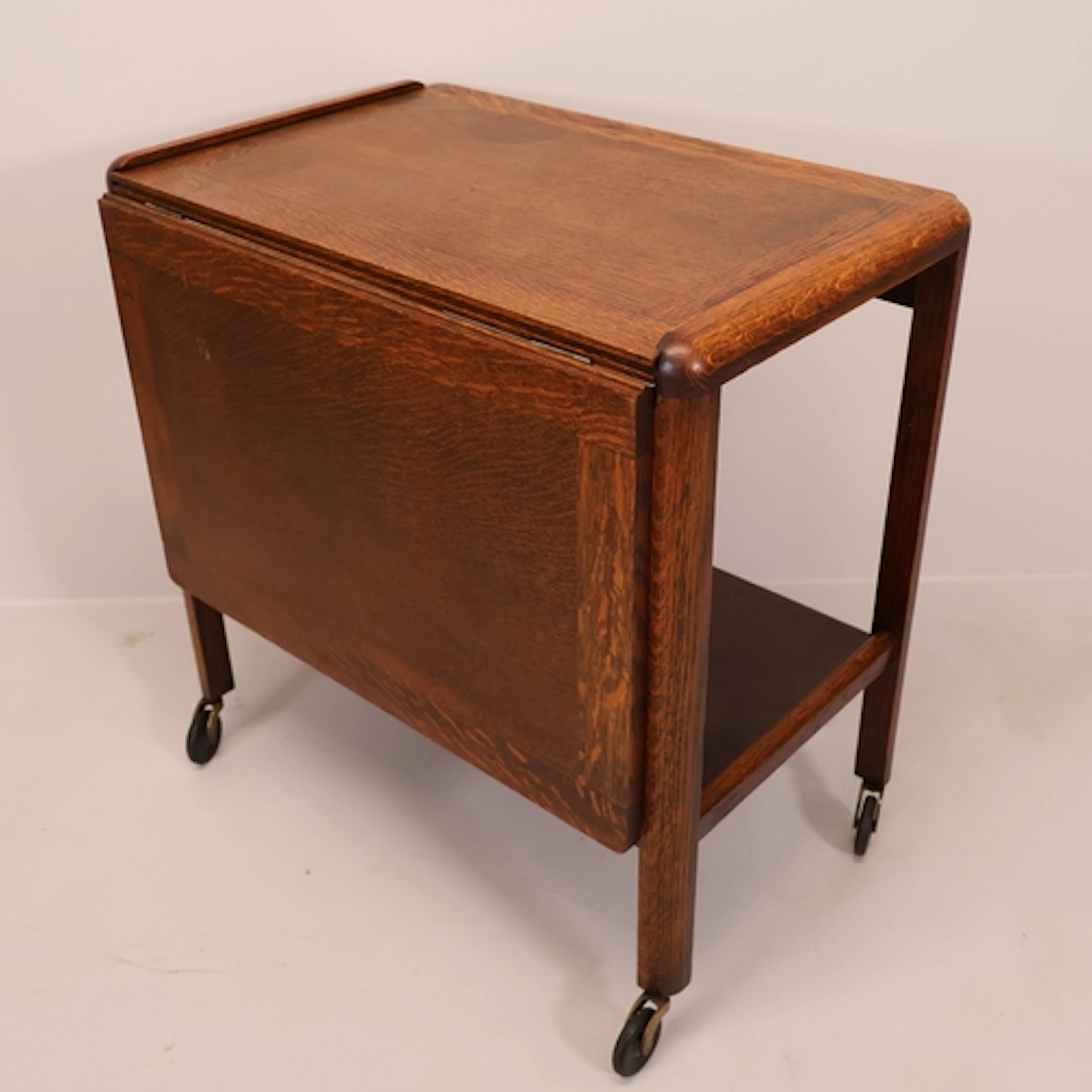 A 1930s oak two-tier drinks trolley, with single drop-leaf. ...