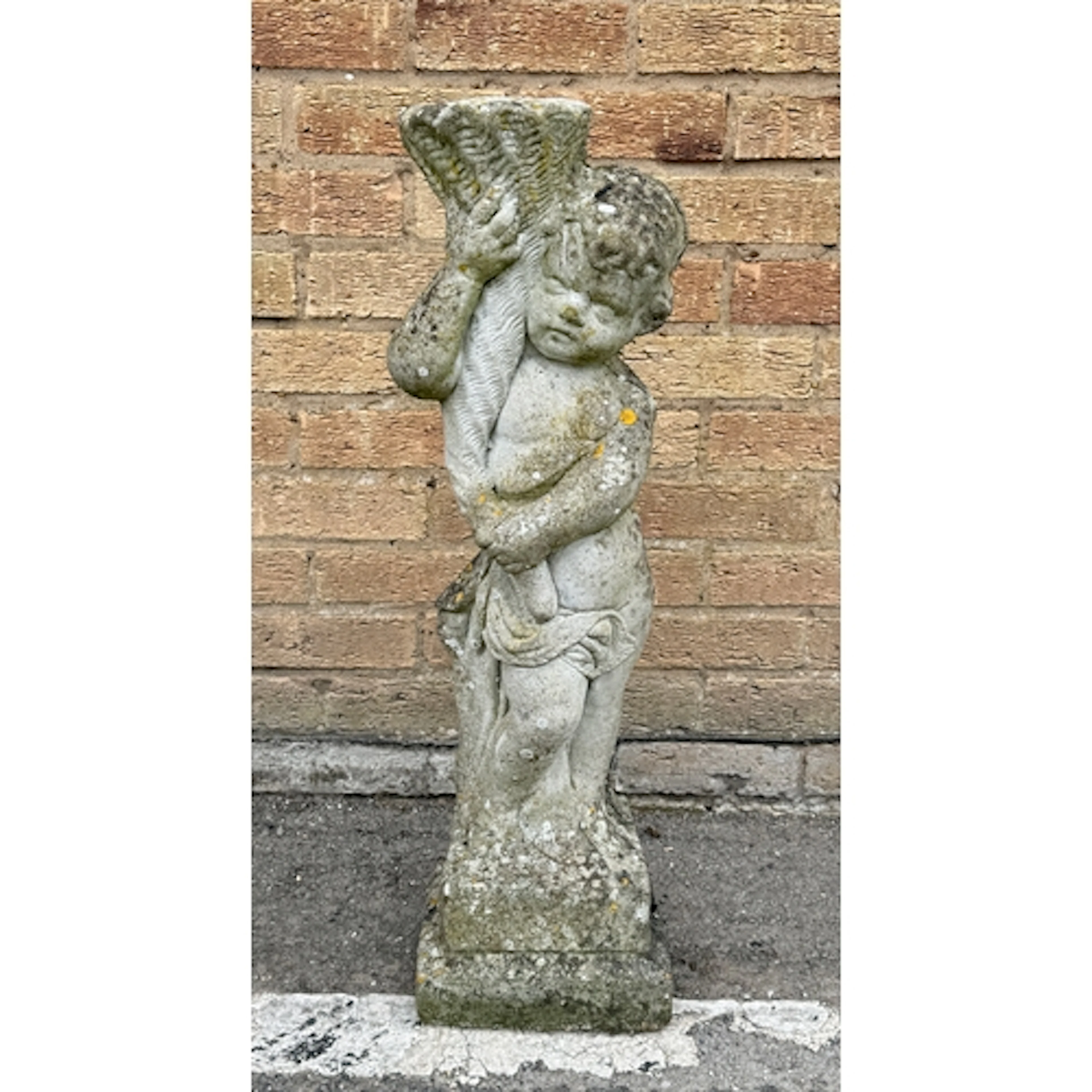 A composite stone garden statue - of a putto holding a cornu...