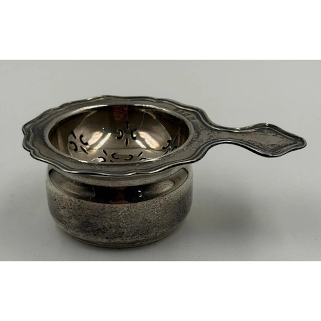 A silver tea strainer set hallmarked for London 1958 by Robe...