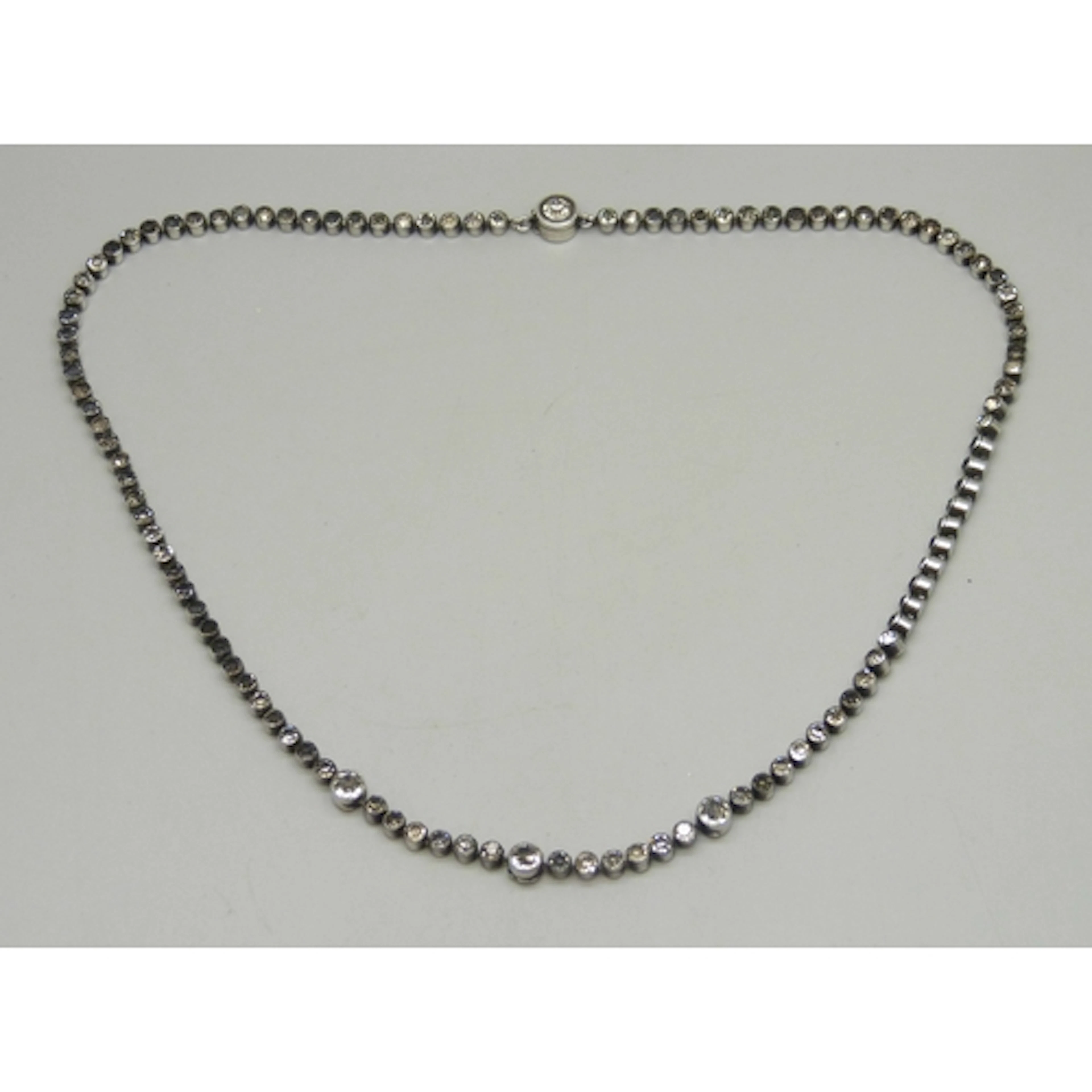 An Art Deco white metal and paste stone set riviere necklace...