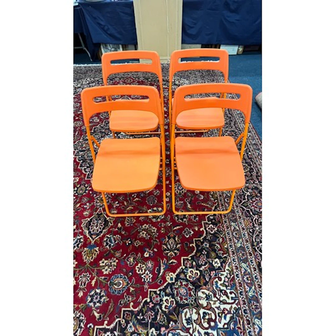 Four bright orange Ikea folding chairs.