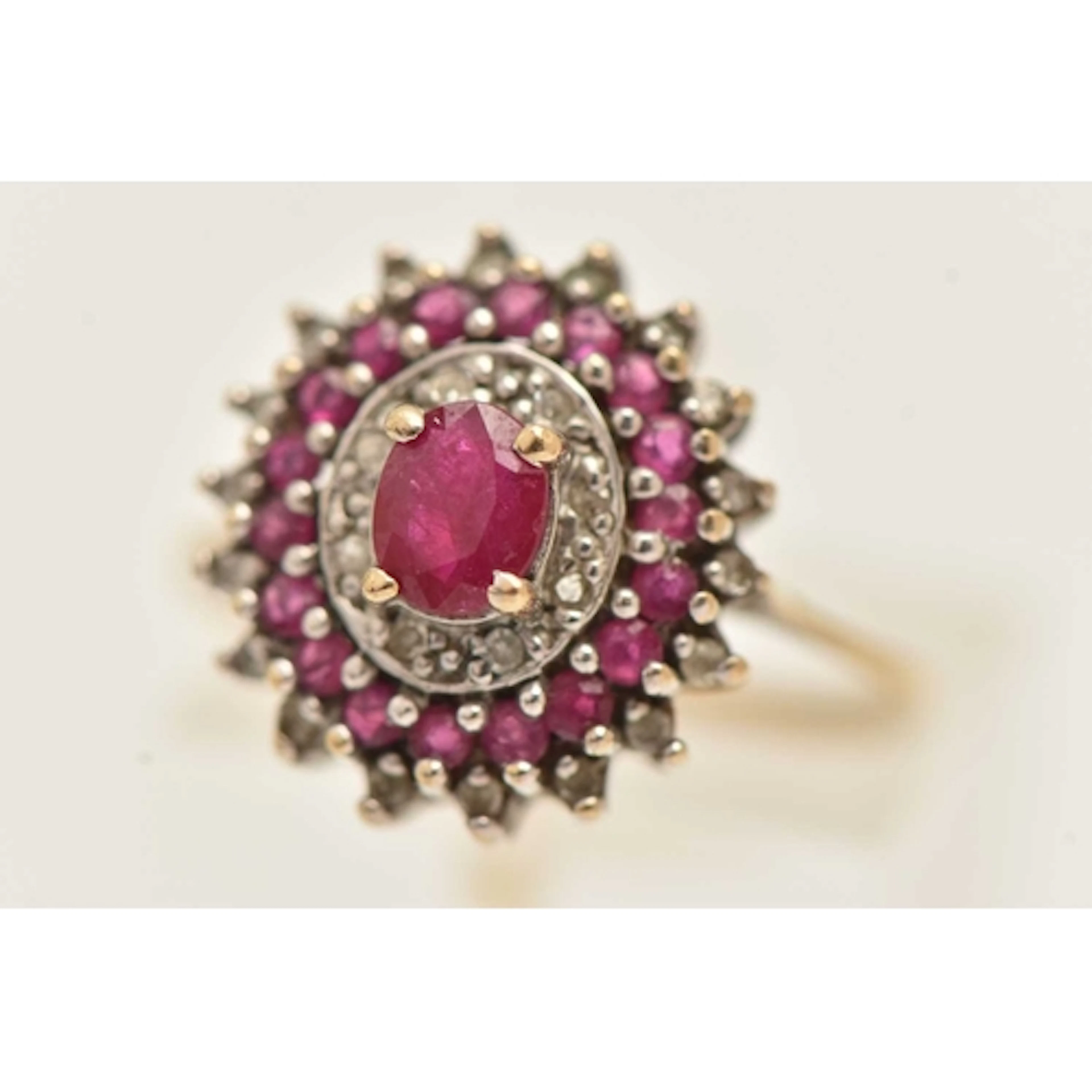 A 9CT GOLD RUBY AND DIAMOND CLUSTER RING, of an oval form, p...
