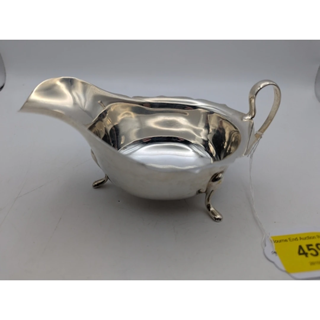 A George V silver sauce boat with a navy edge on pad feet, h...