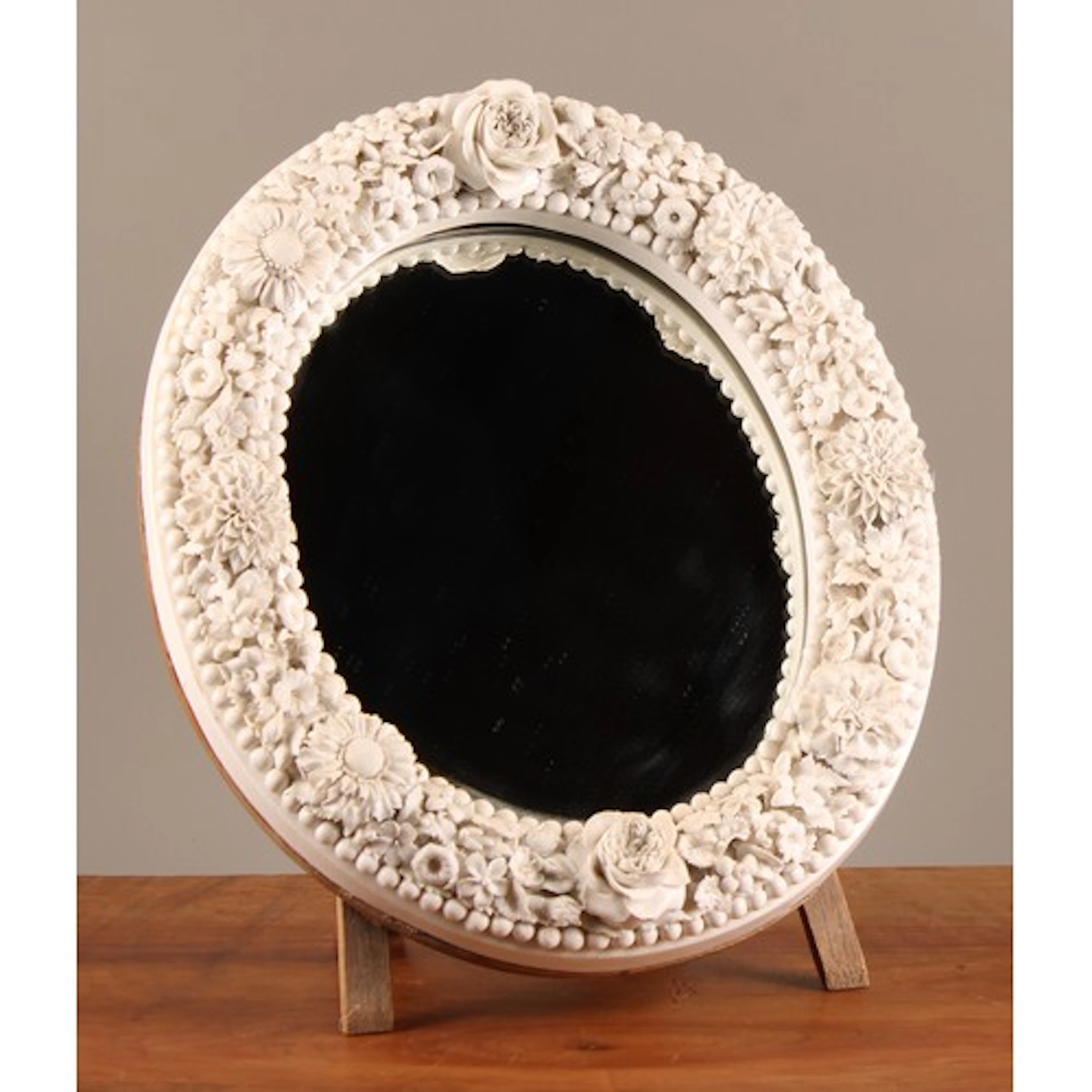 An English porcelain oval dressing table looking glass, in t...