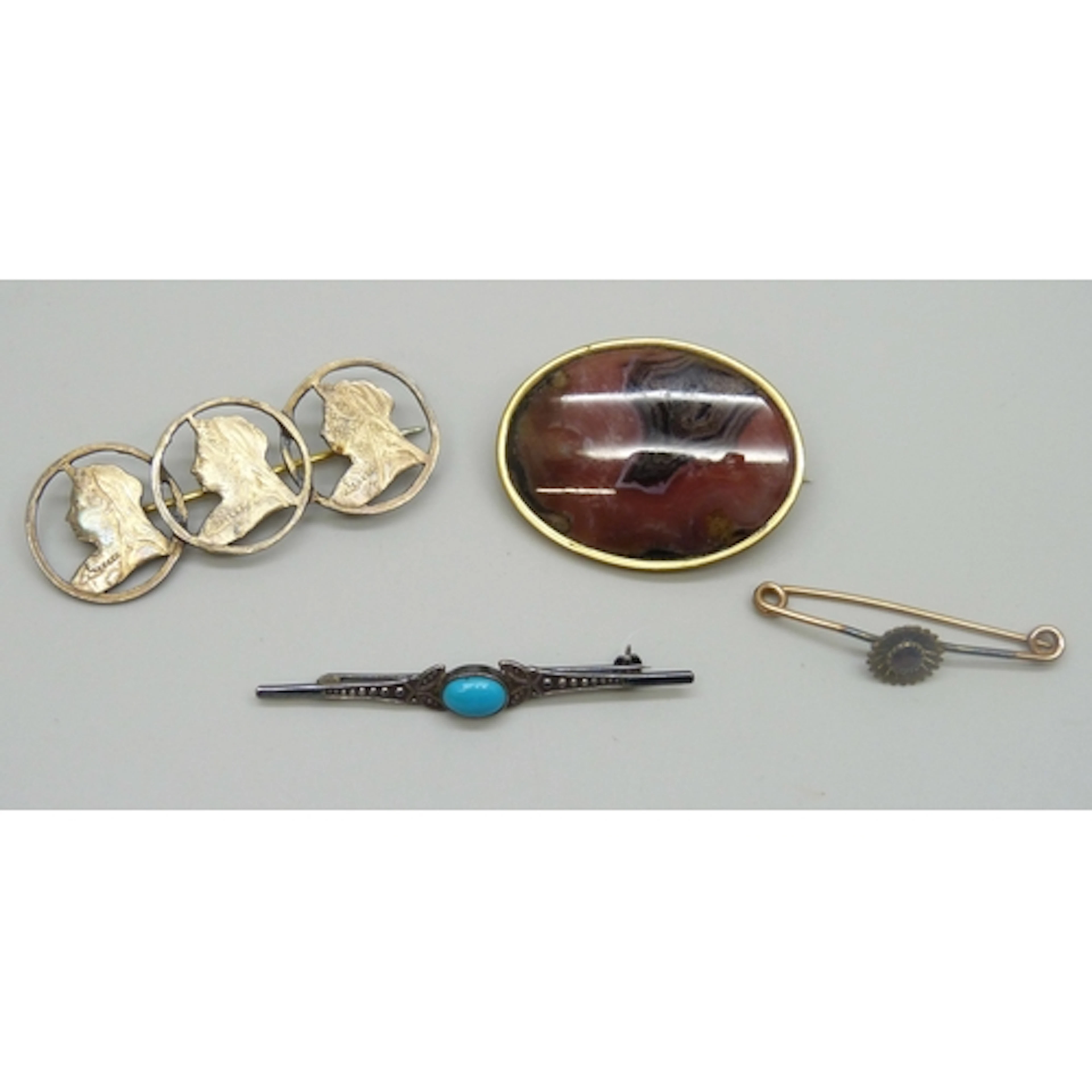 A yellow metal and garnet brooch with applied gilt decoratio...