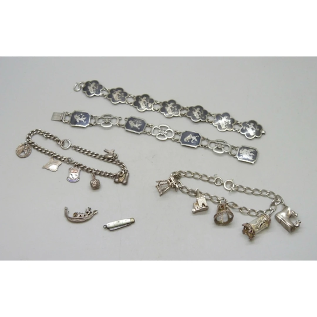 A silver charm bracelet, a white metal charm bracelet, a sil...
