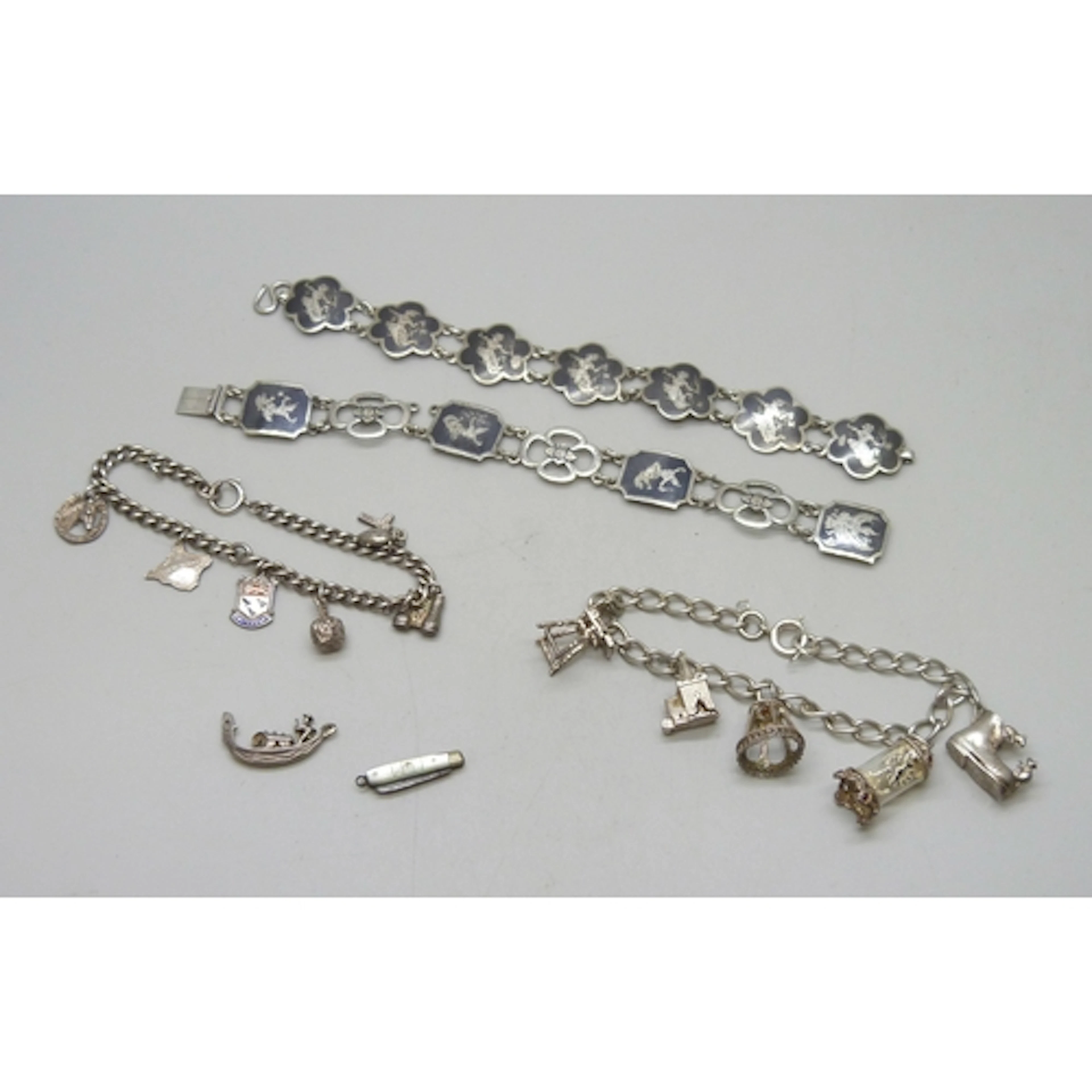A silver charm bracelet, a white metal charm bracelet, a sil...
