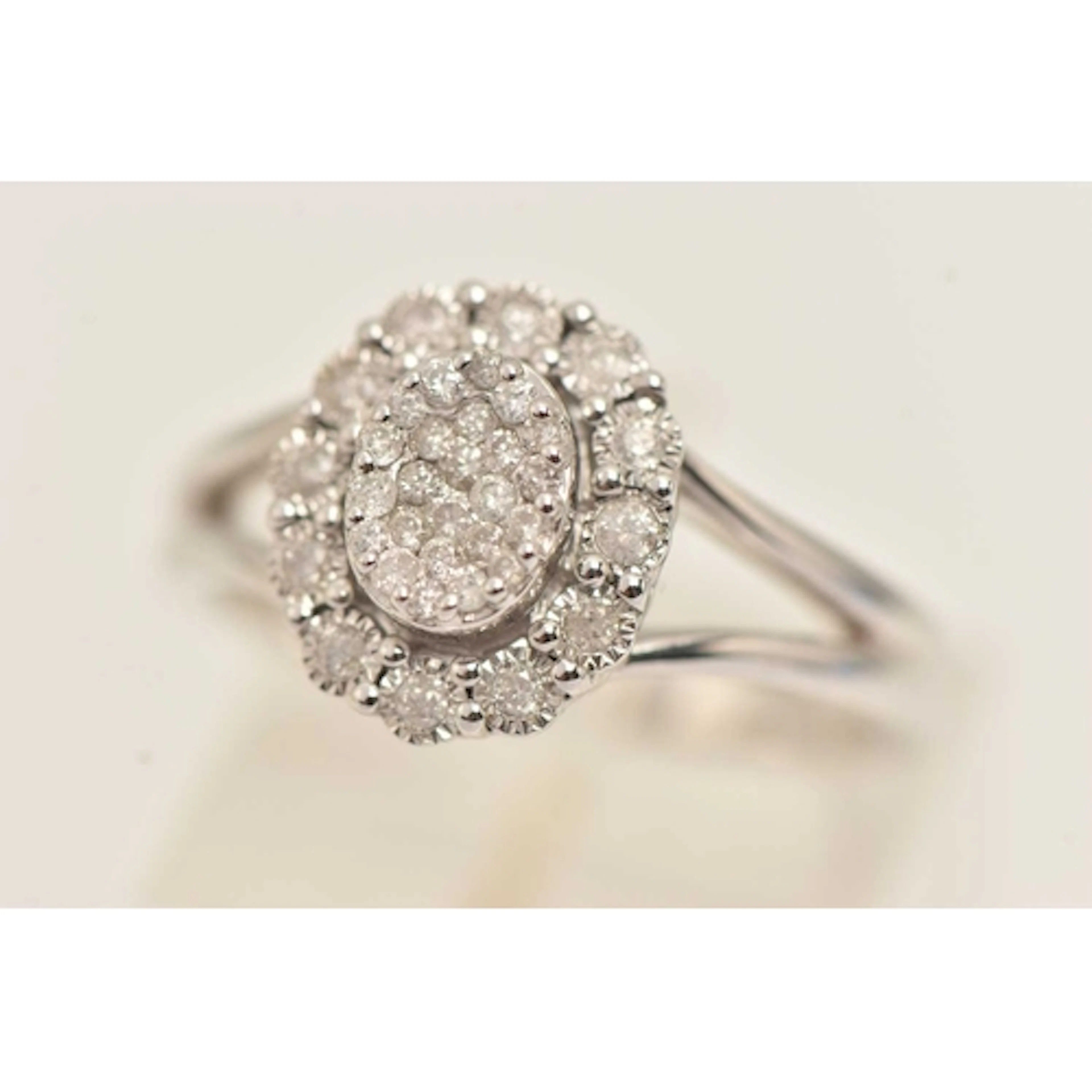 A 9CT GOLD DIAMOND CLUSTER RING, of an oval form, the centre...