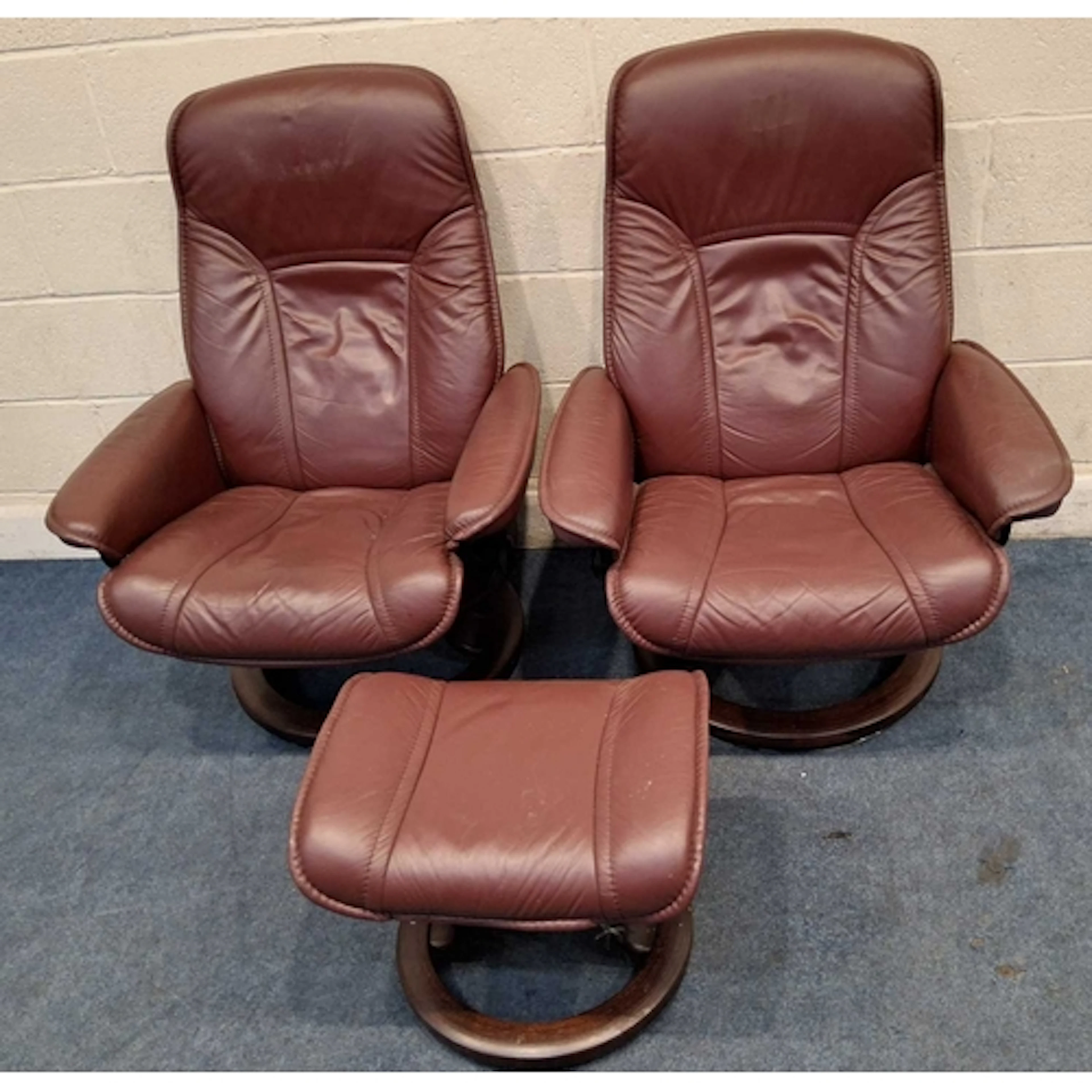 A PAIR OF EKORNESS STRESSLESS BURGUNDY LEATHER SWIVEL RECLIN...