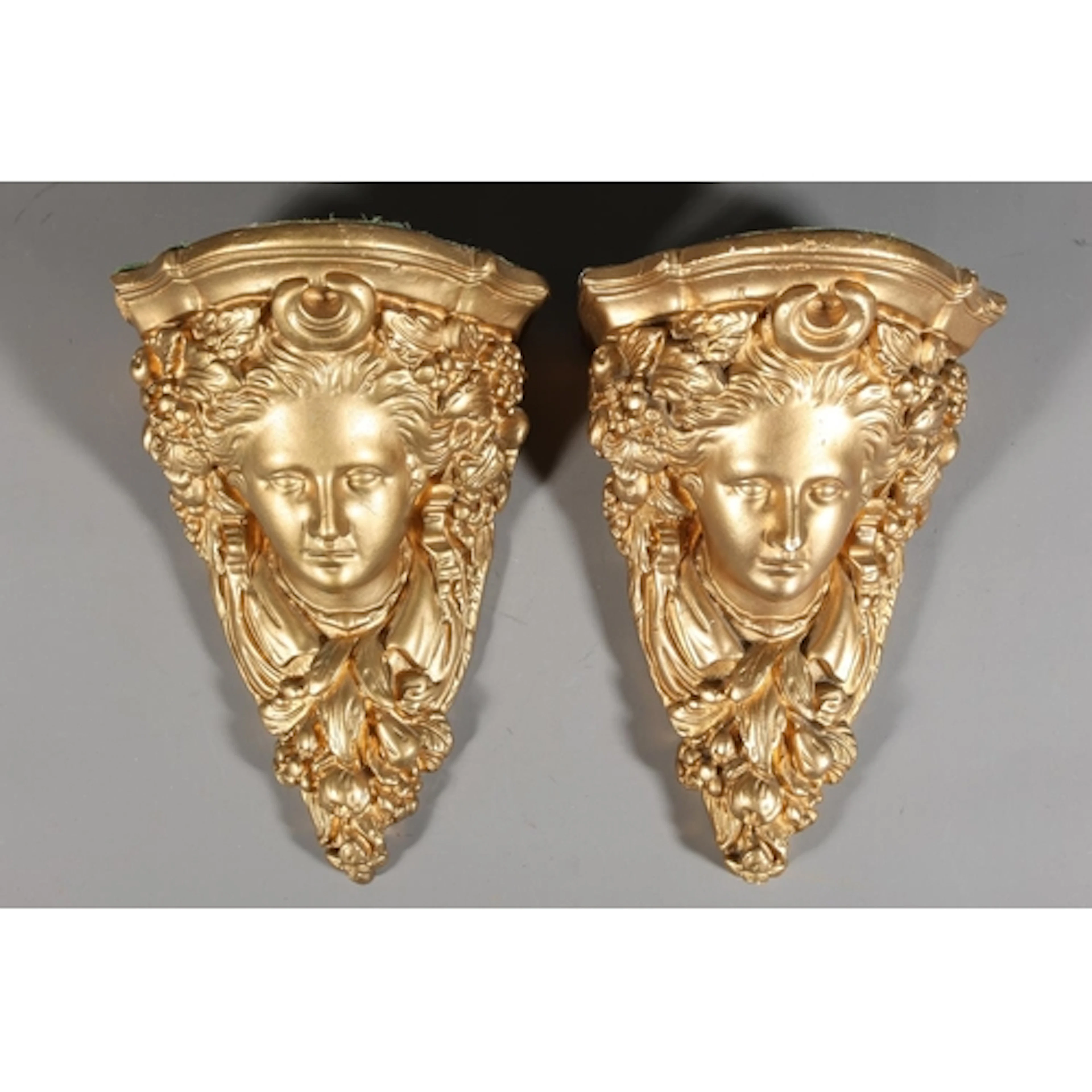 Pair of gilded plaster wall brackets modelled as masks.