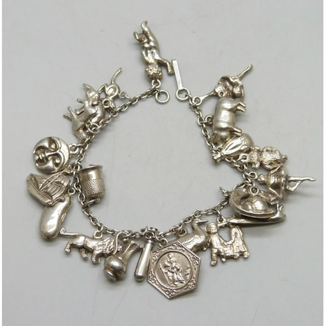 A white metal charm bracelet with a collection of silver and...