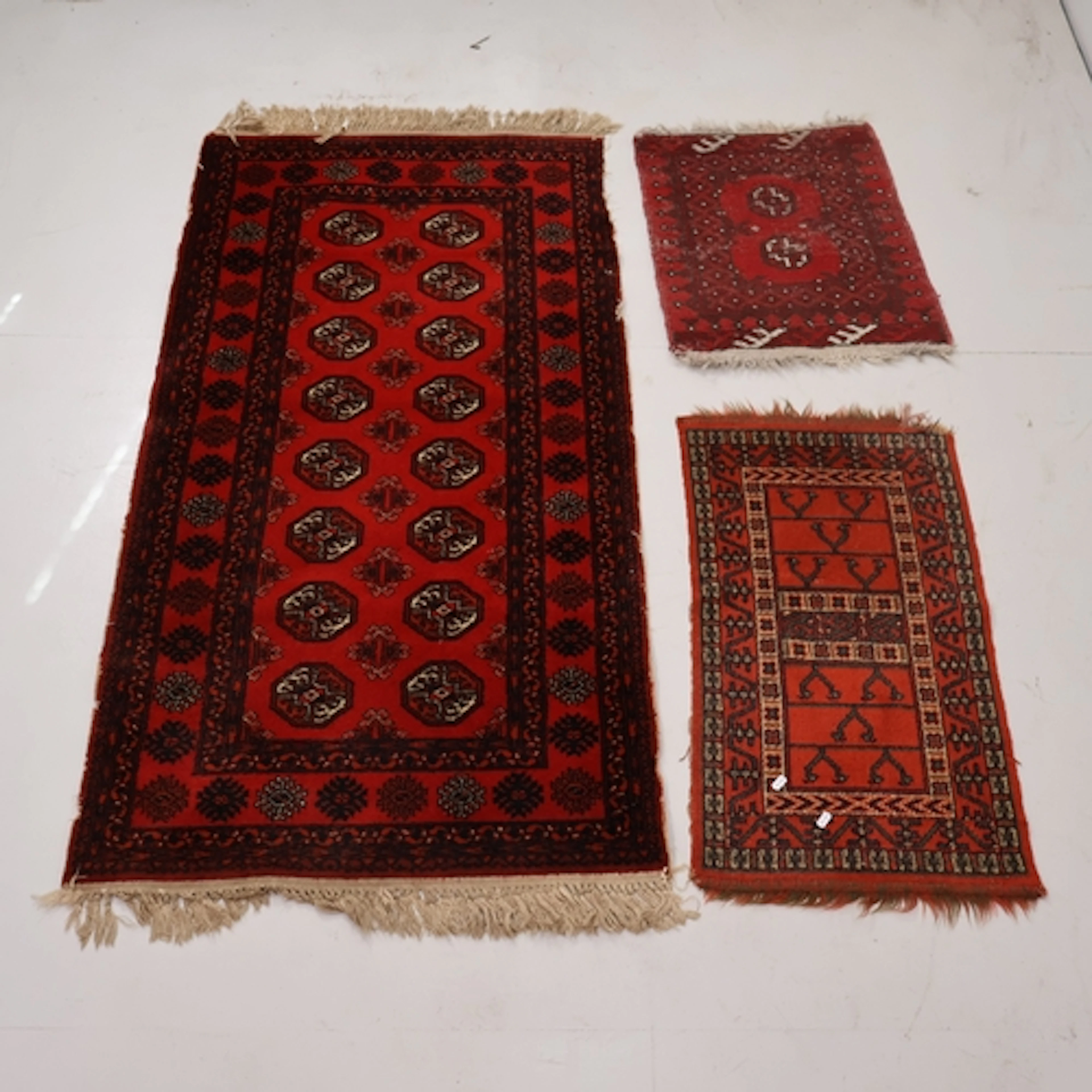 A red ground Afghan rug and two Afghan red ground mats (3), ...