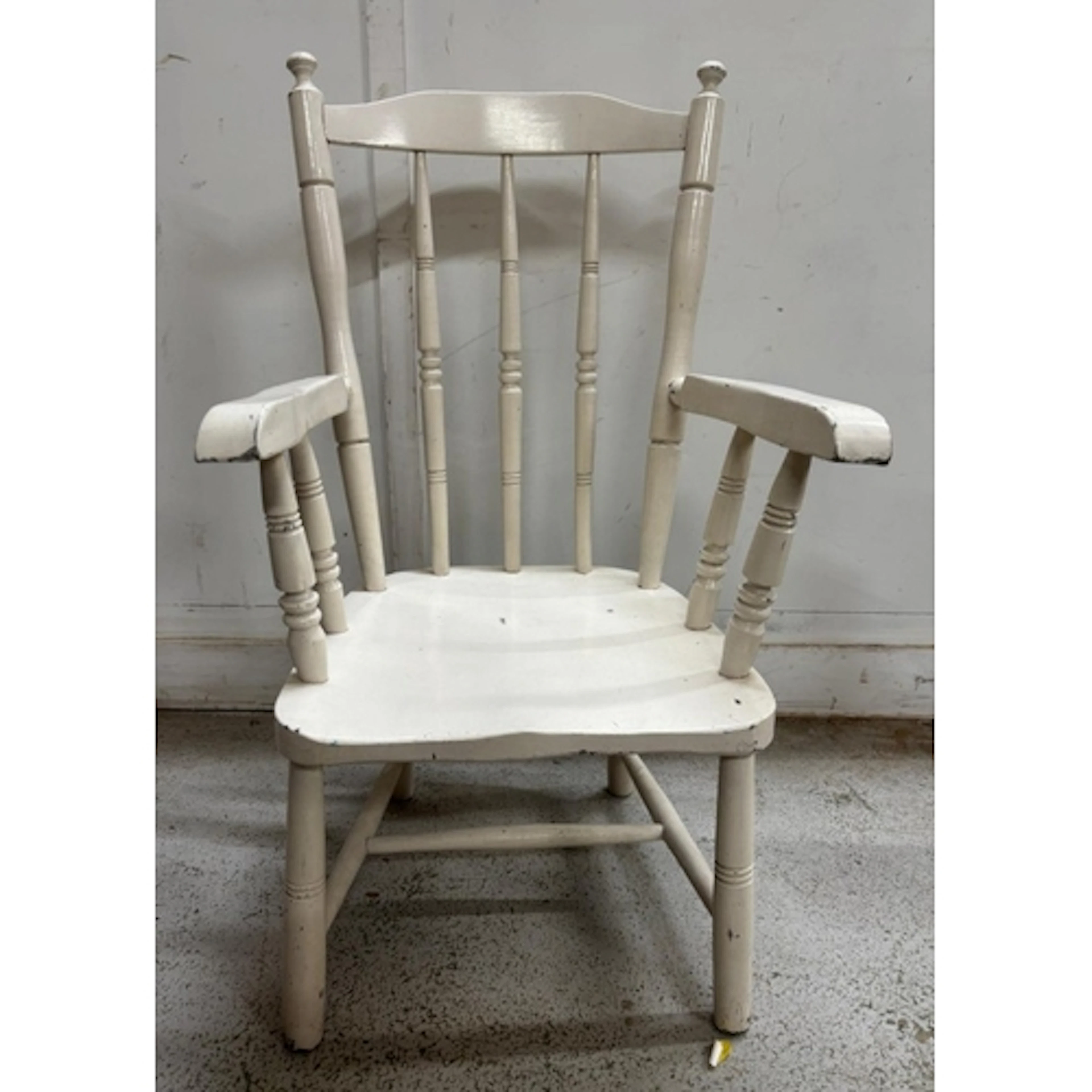 A vintage wooden armchair in a distressed white paint with c...