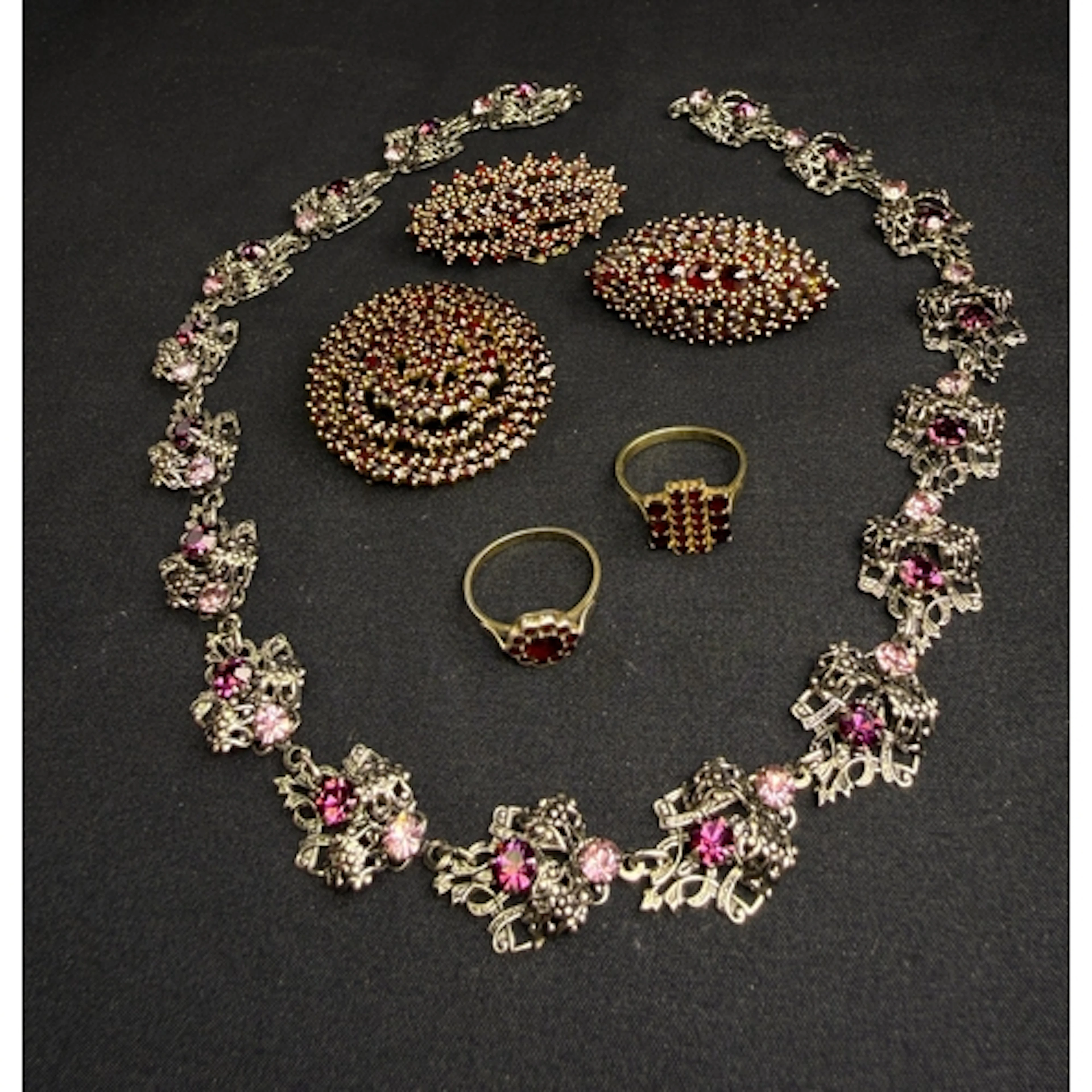A vintage circular brooch with bands of cut red garnets in c...