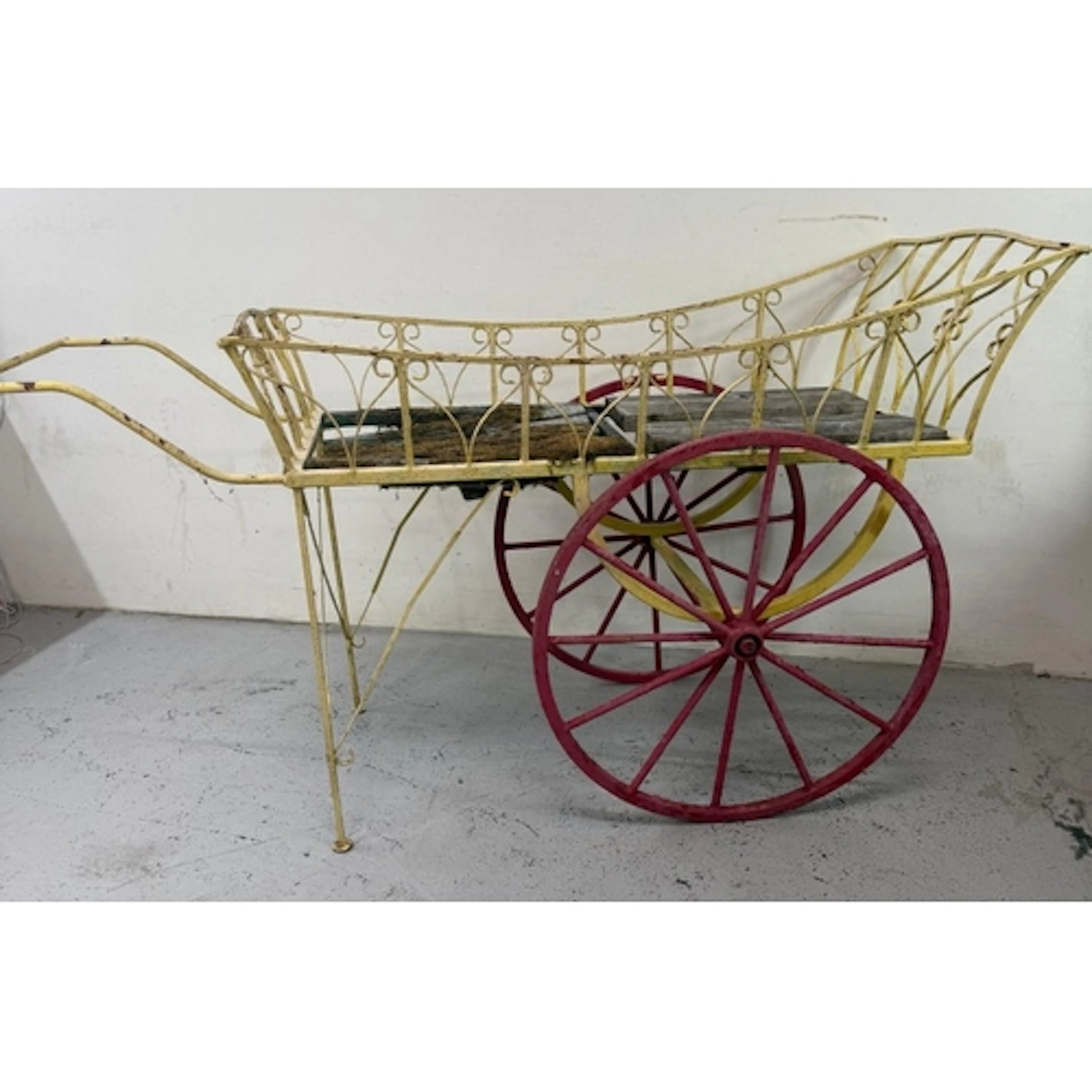 A vintage wrought iron display cart with red wheels. Height ...