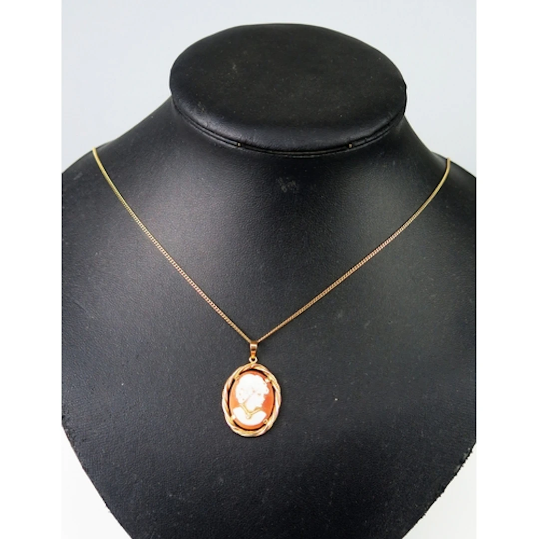 A shell cameo pendant in an 18ct yellow gold setting decorat...