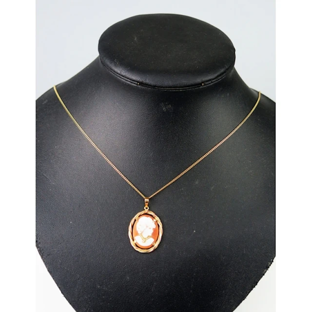 A shell cameo pendant in an 18ct yellow gold setting decorat...