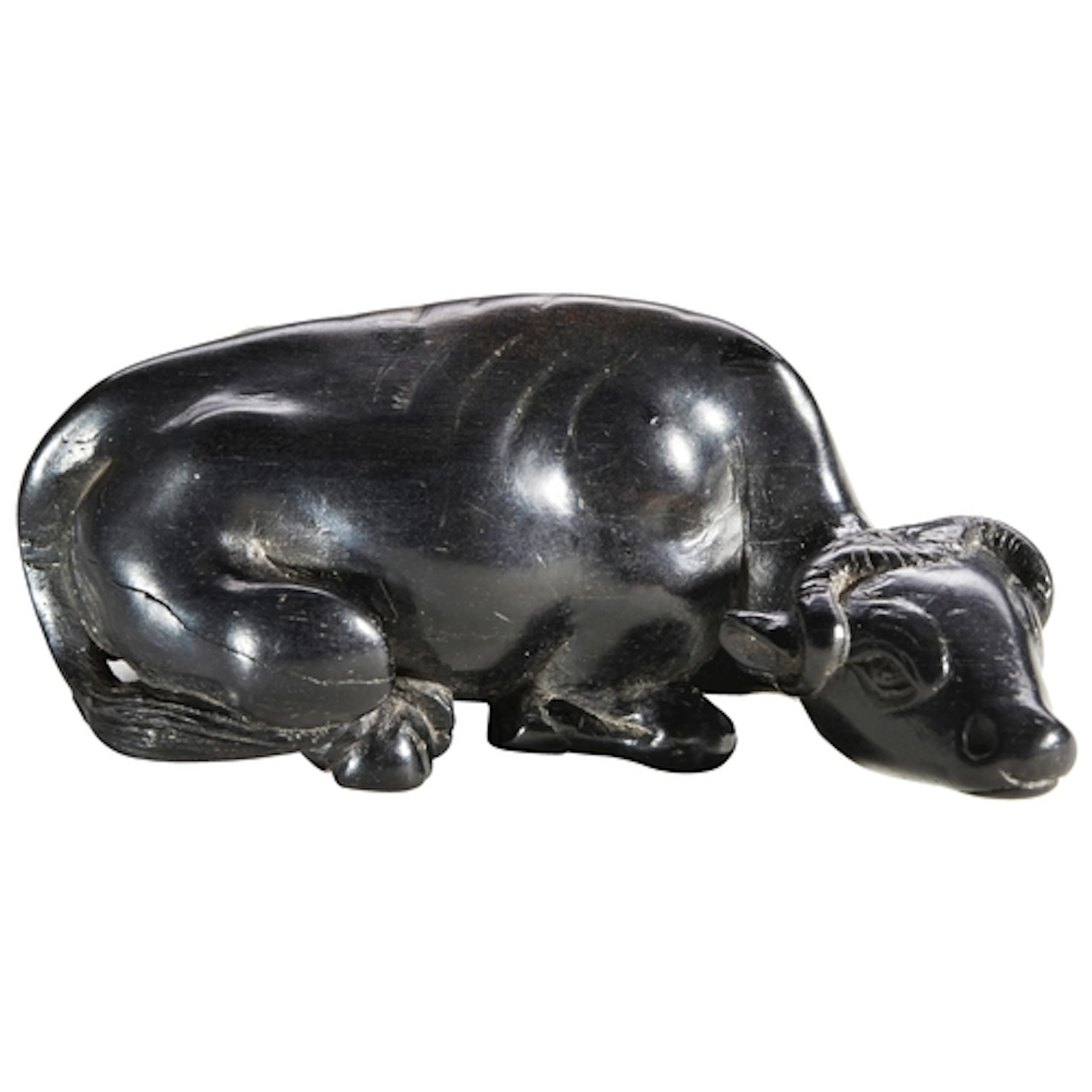 A JAPANESE CARVED BLACK HARDWOOD NETSUKE OF A WATER BUFFALO ...