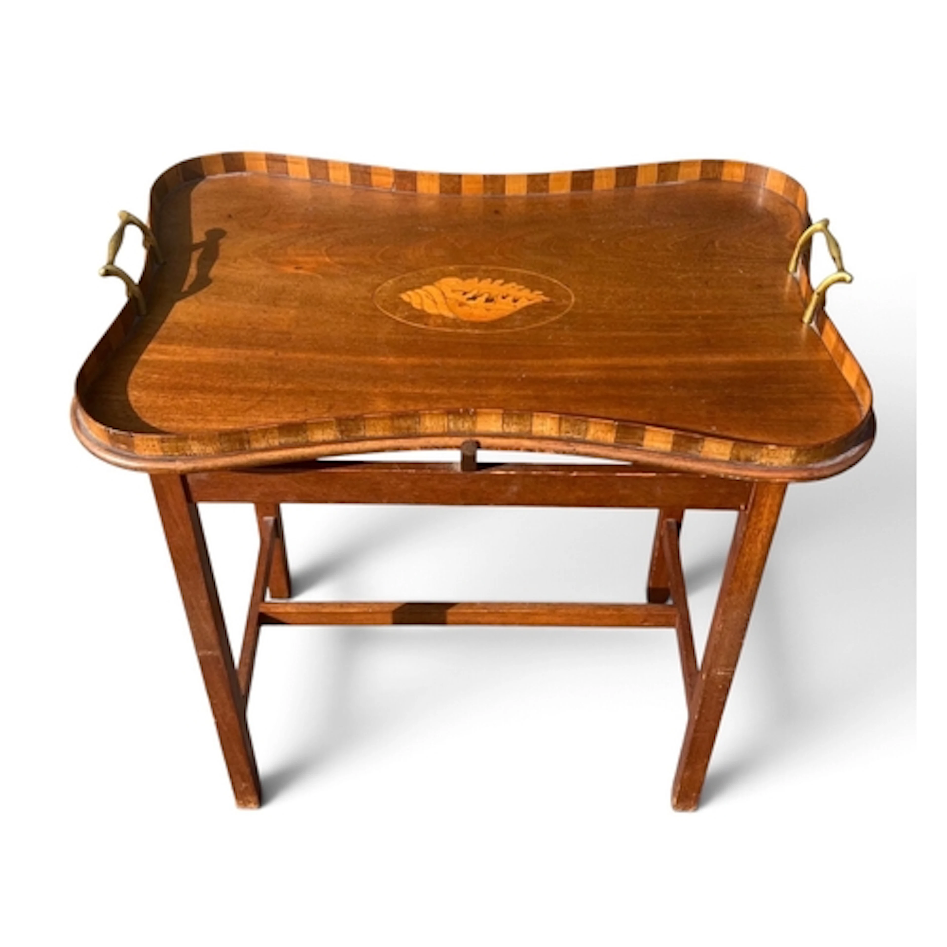 AN EDWARDIAN MAHOGANY SHAPED TRAY TABLE The top with marquet...