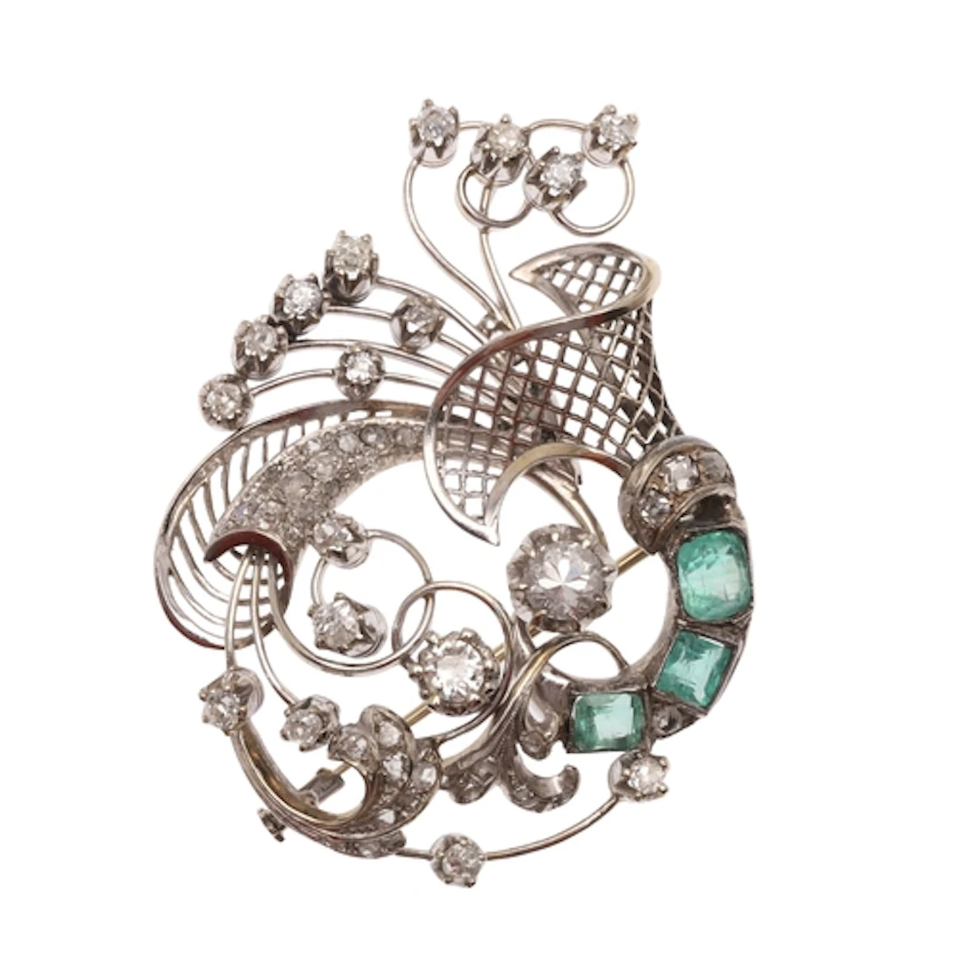 AN EMERALD AND DIAMOND BROOCH. of scrolling form, set with t...