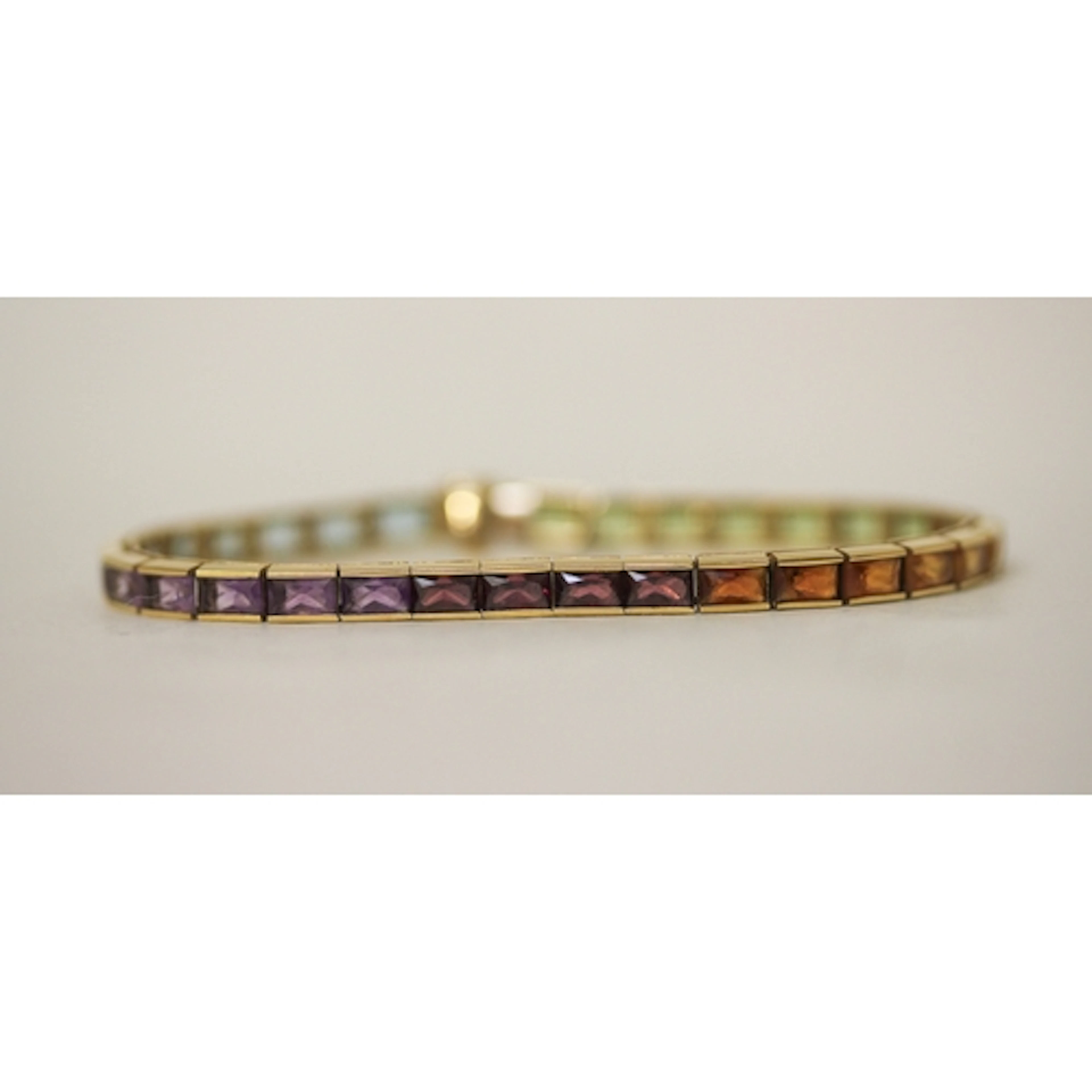 A gold rainbow tennis bracelet, comprising multi coloured ch...