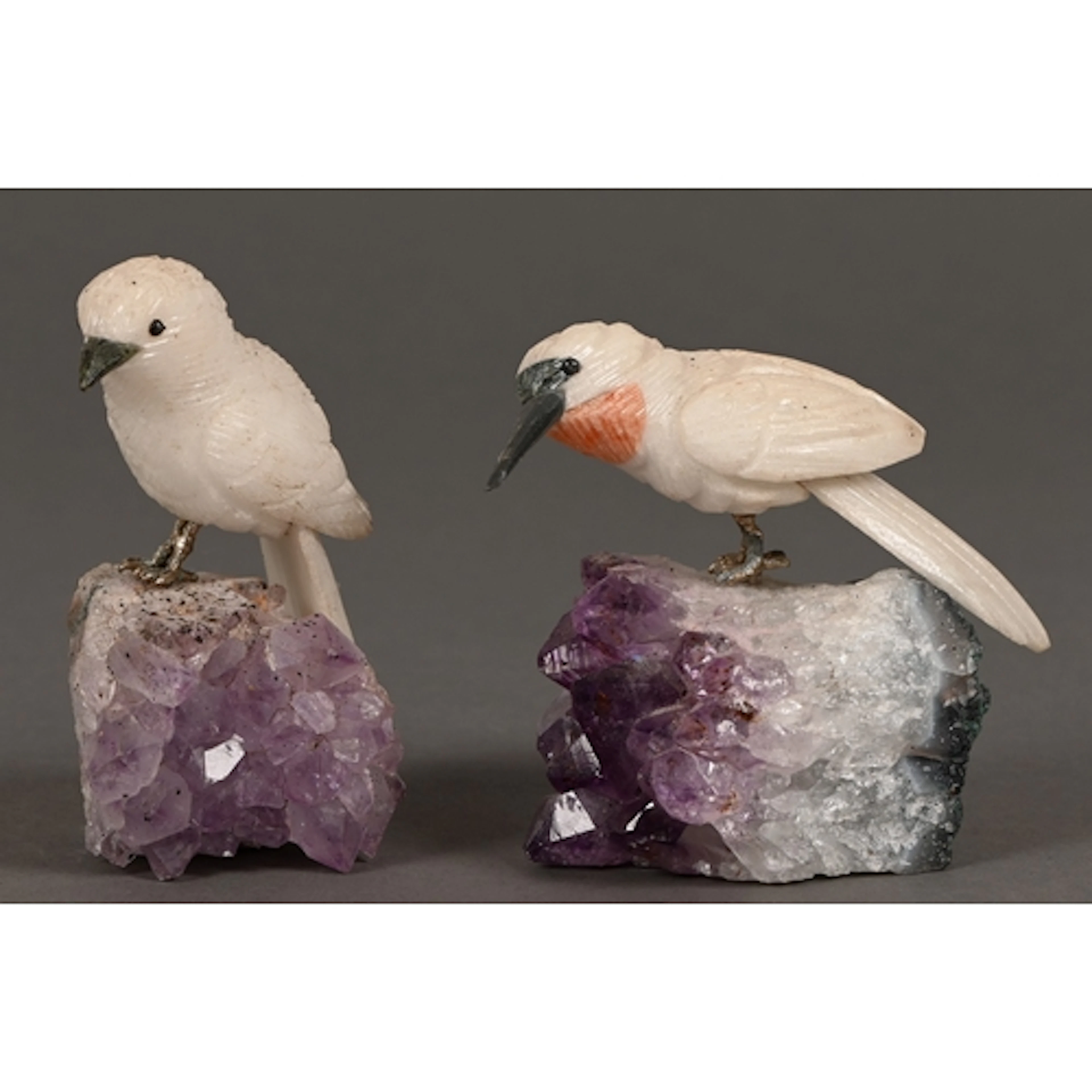 A pair of carved hardstone birds, with silver coloured metal...