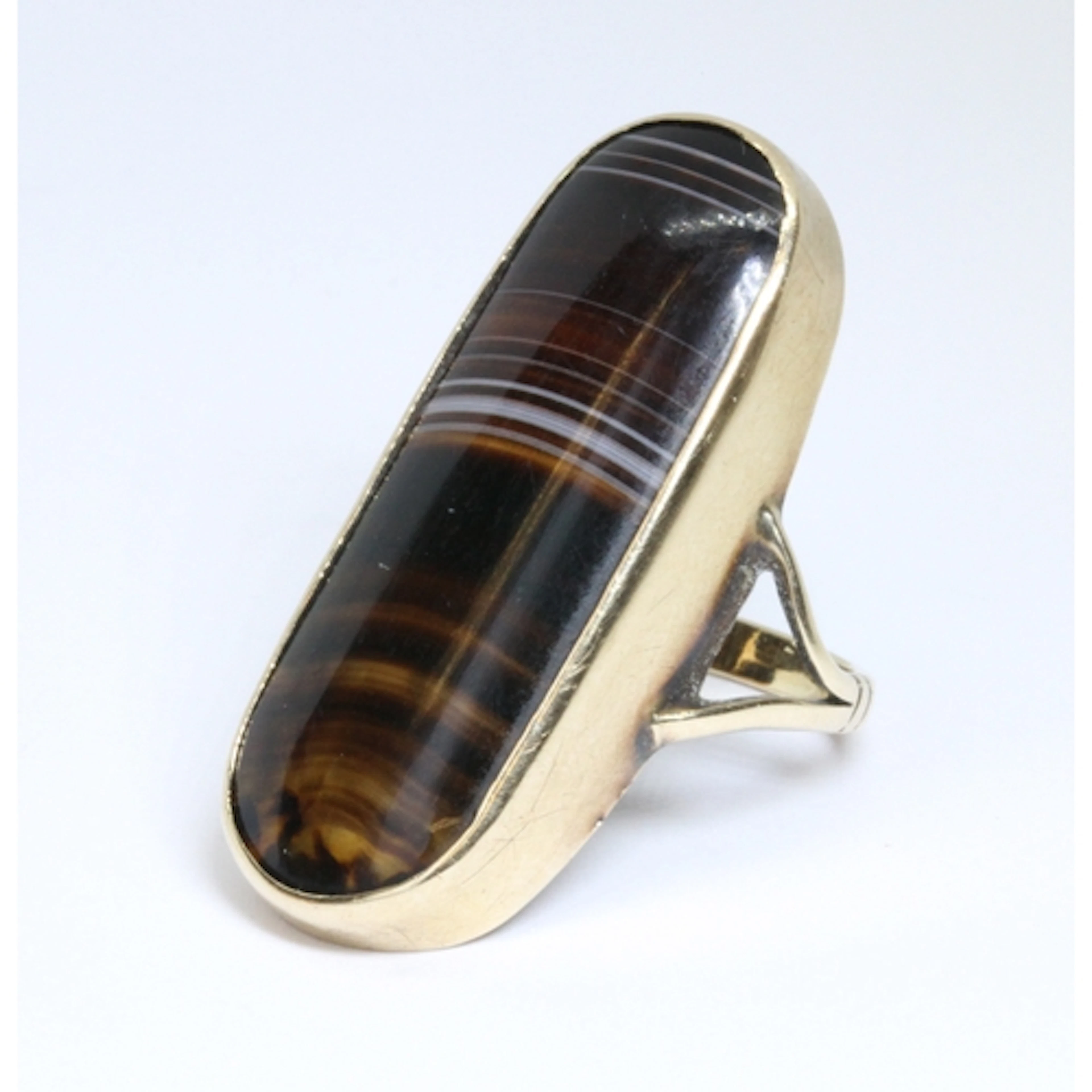 A yellow metal onyx ring, the oblong cabochon measuring appr...