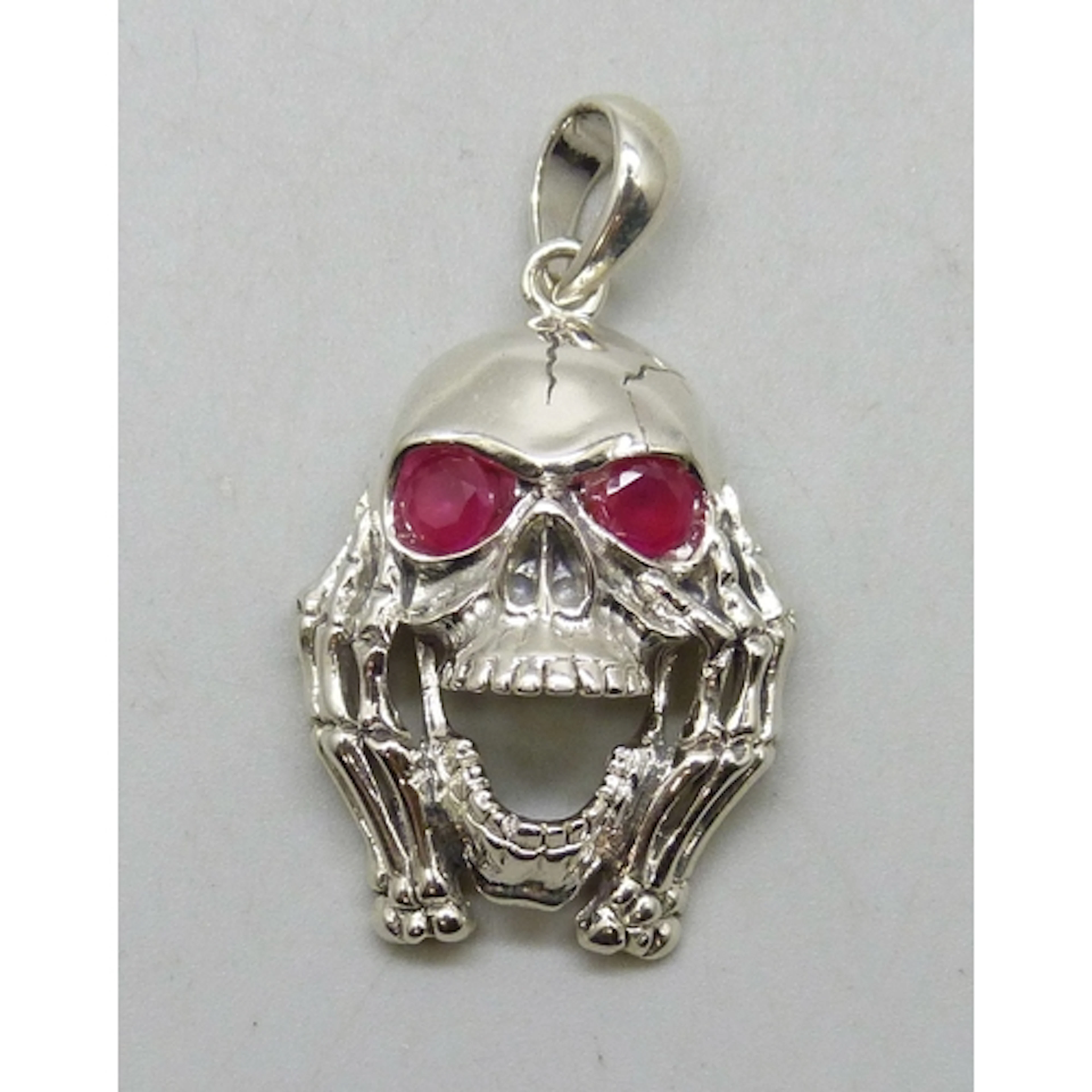 A silver necklace pendant in the form of a skull set with ru...