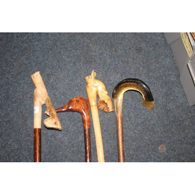 Four walking sticks with carved heads to include a rabbit, o...