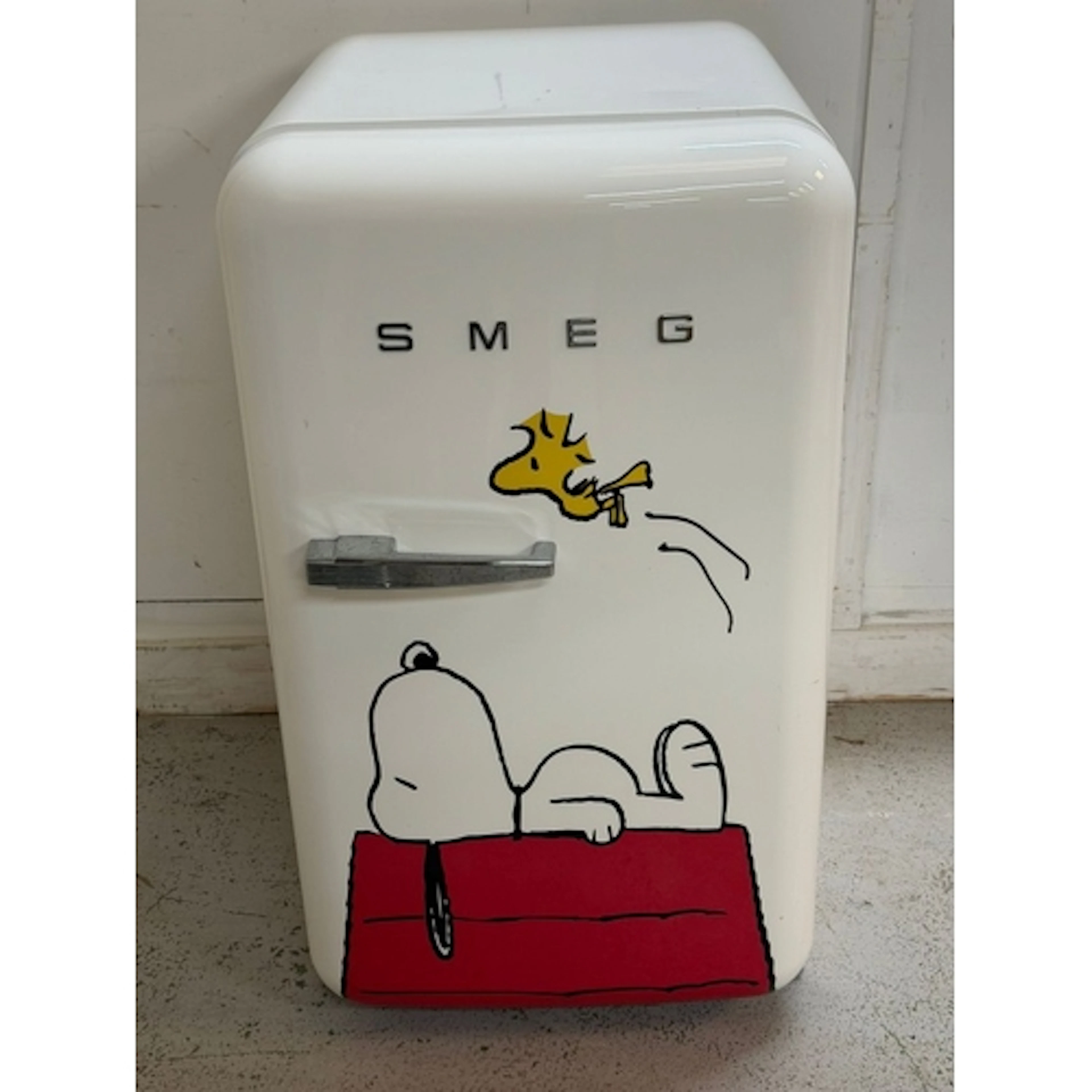 A Smeg and Peanuts fridge collaboration showing Snoopy lyin...