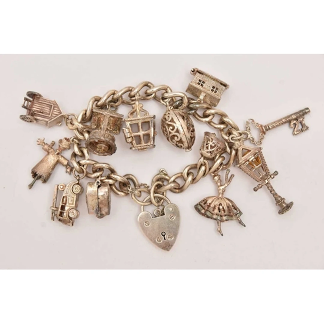 A WHITE METAL CURB LINK CHARM BRACELET, fitted with a heart ...
