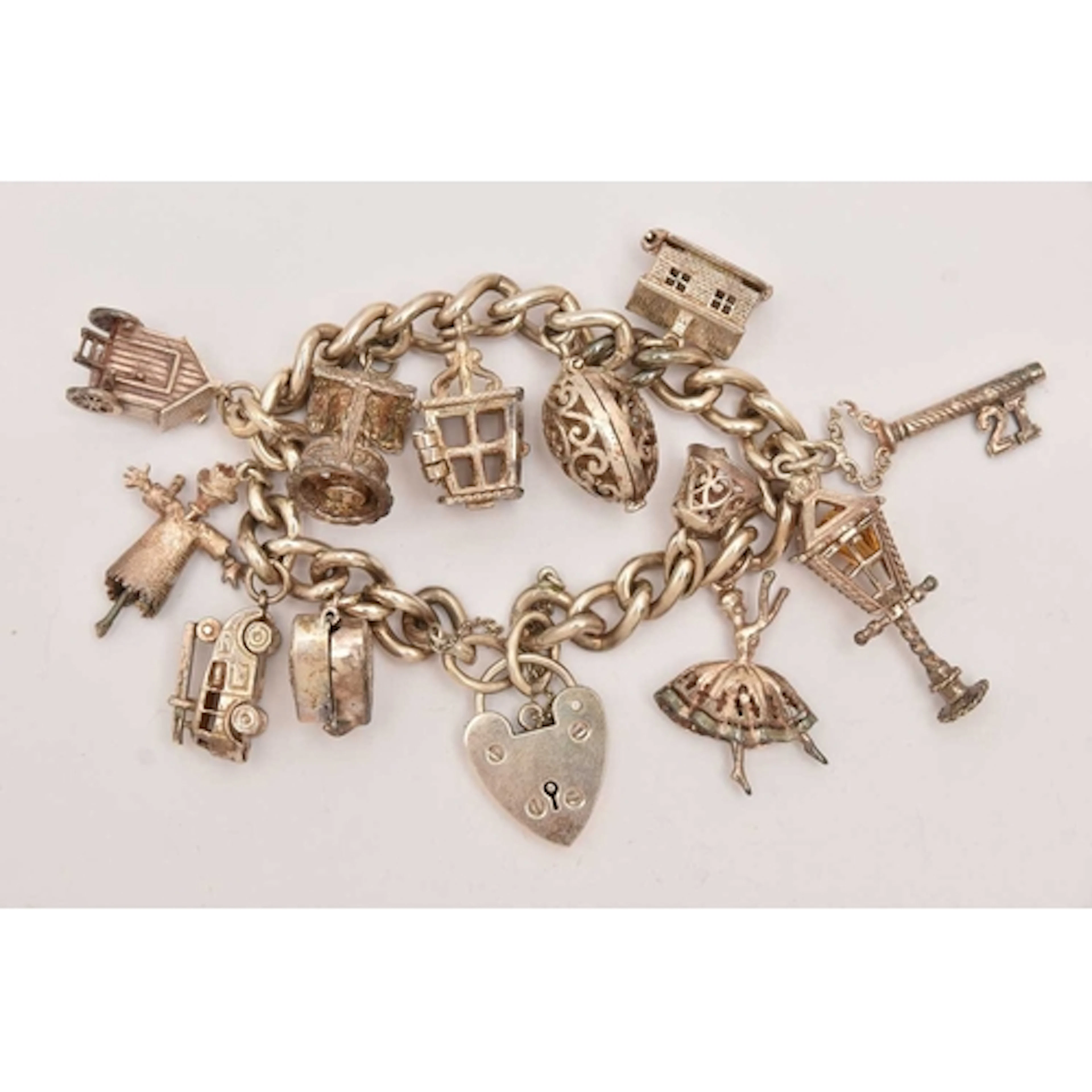 A WHITE METAL CURB LINK CHARM BRACELET, fitted with a heart ...