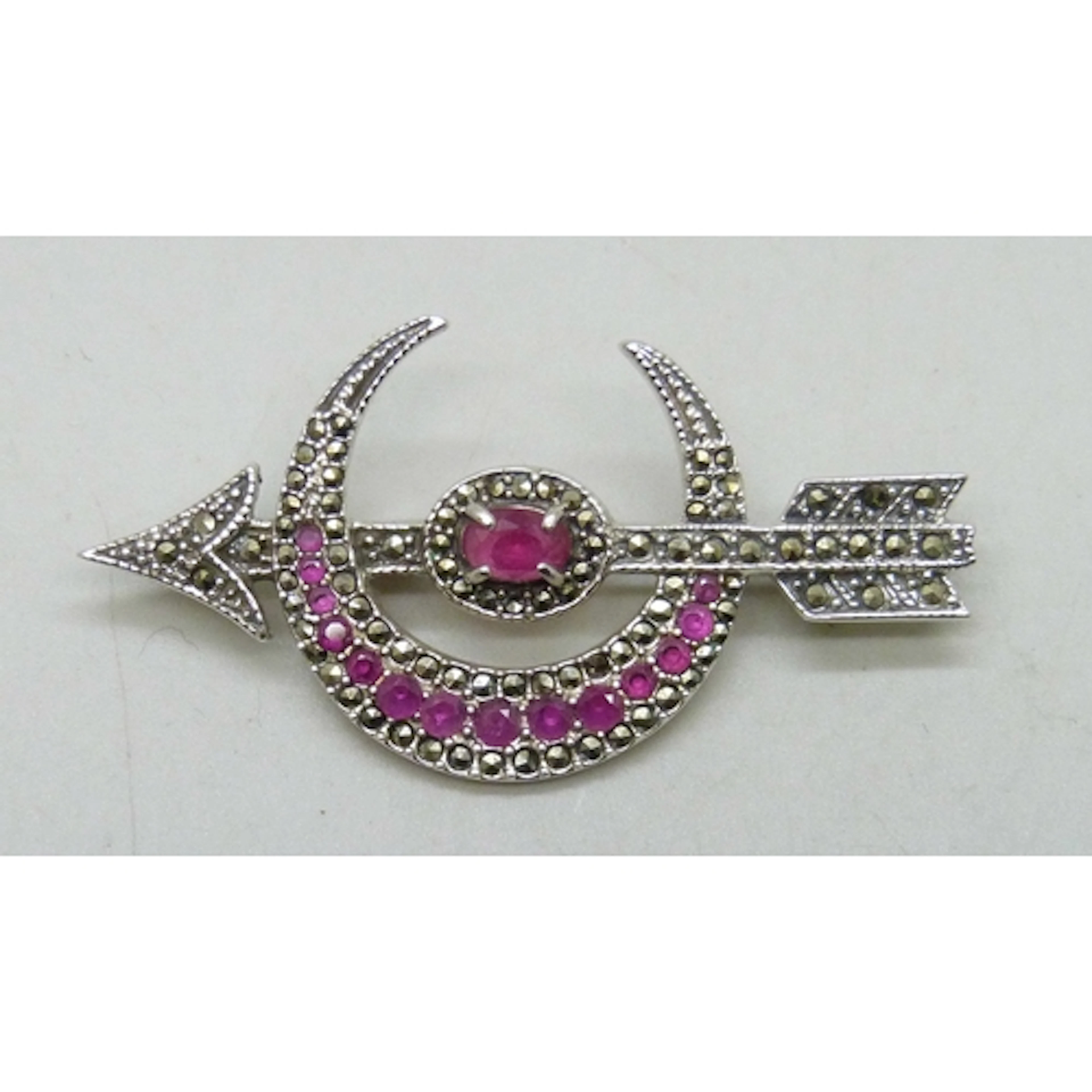 A silver crescent and arrow design brooch set with rubies an...