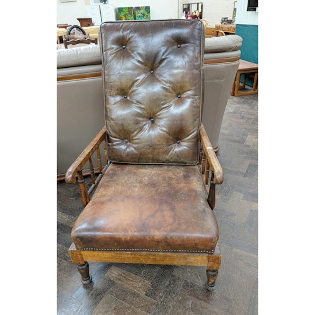 A 1920's open arm chair with buttoned leather distressed cus...