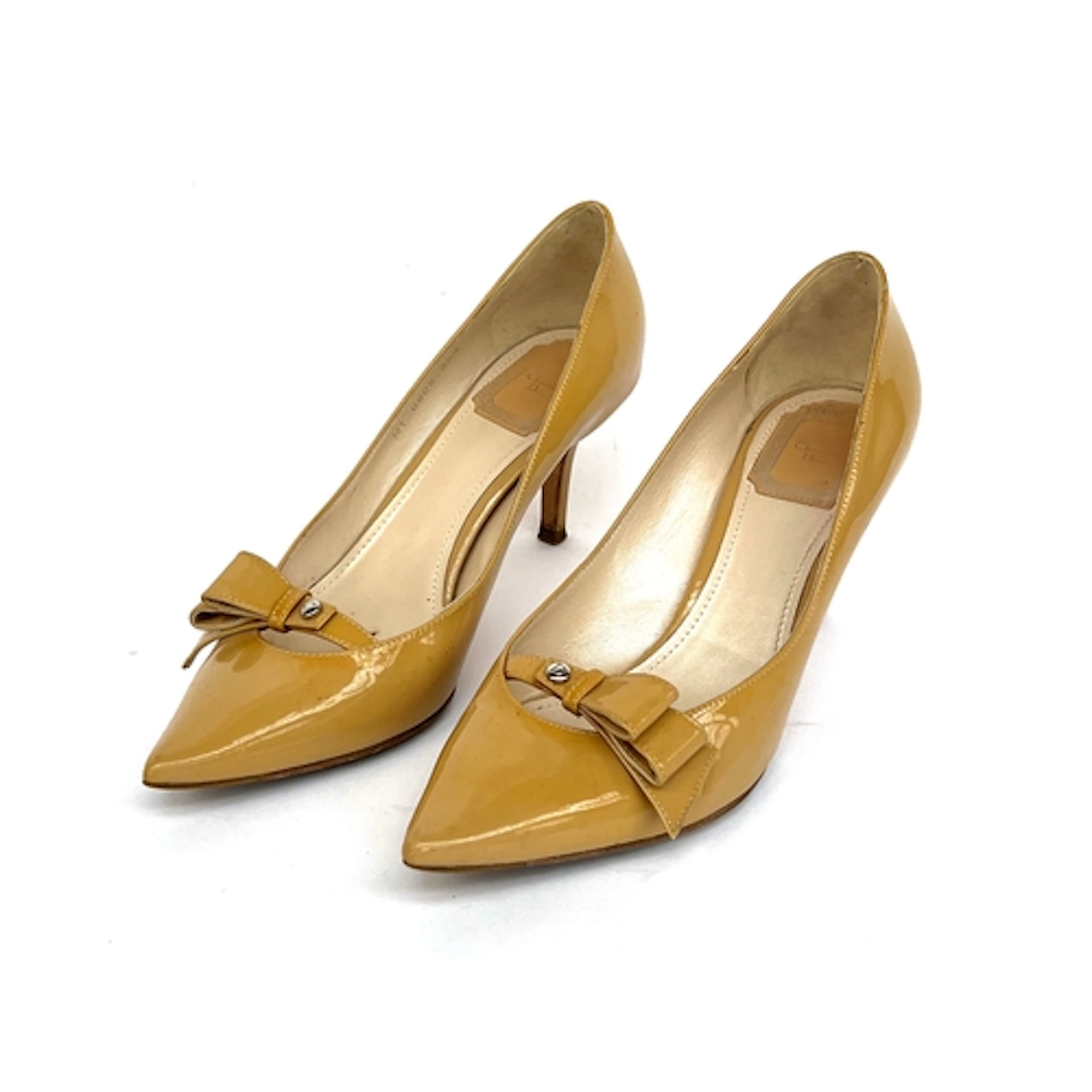A pair of Christian Dior tan patent leather heels with bow d...