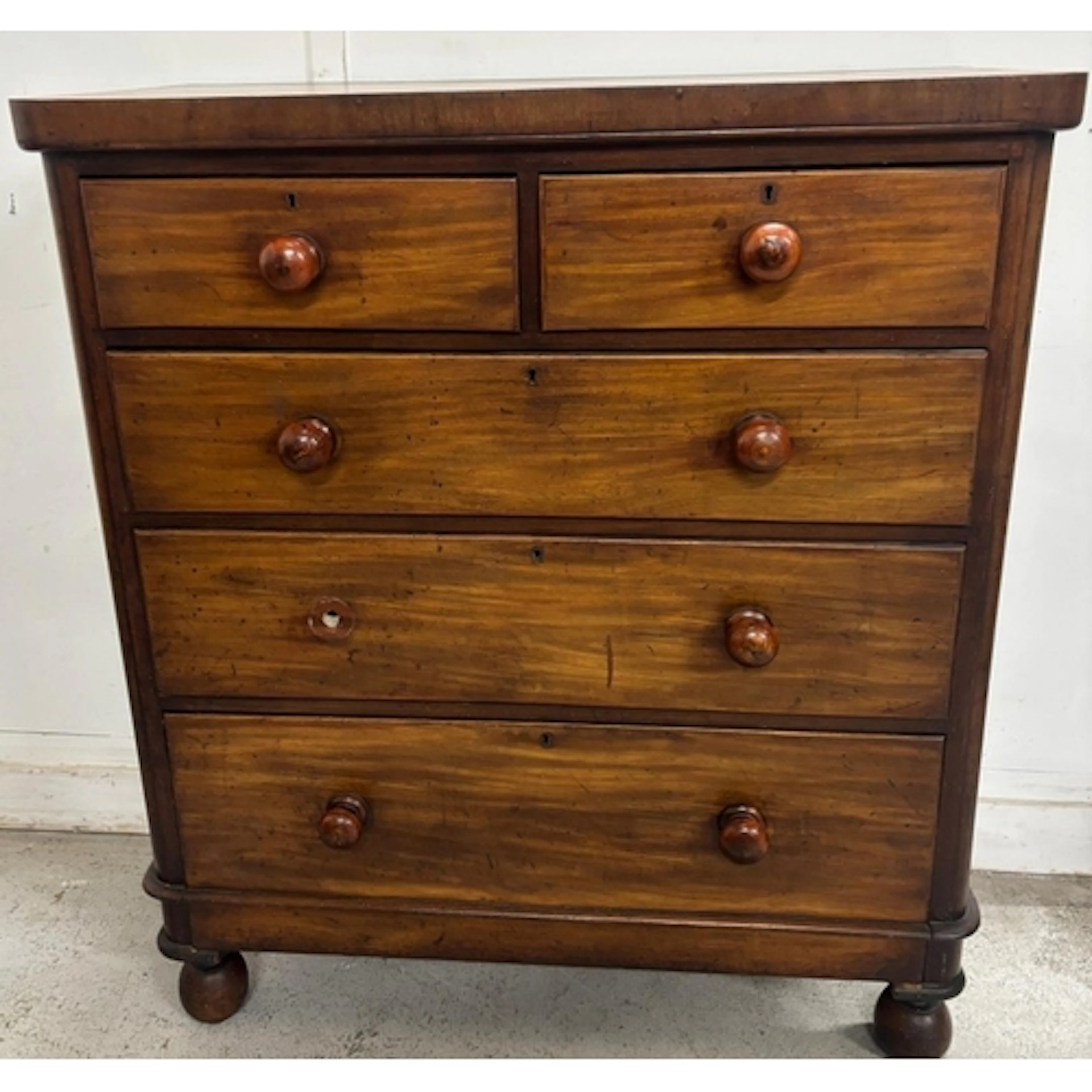 A two-over-three mahogany chest of drawers featuring classic...