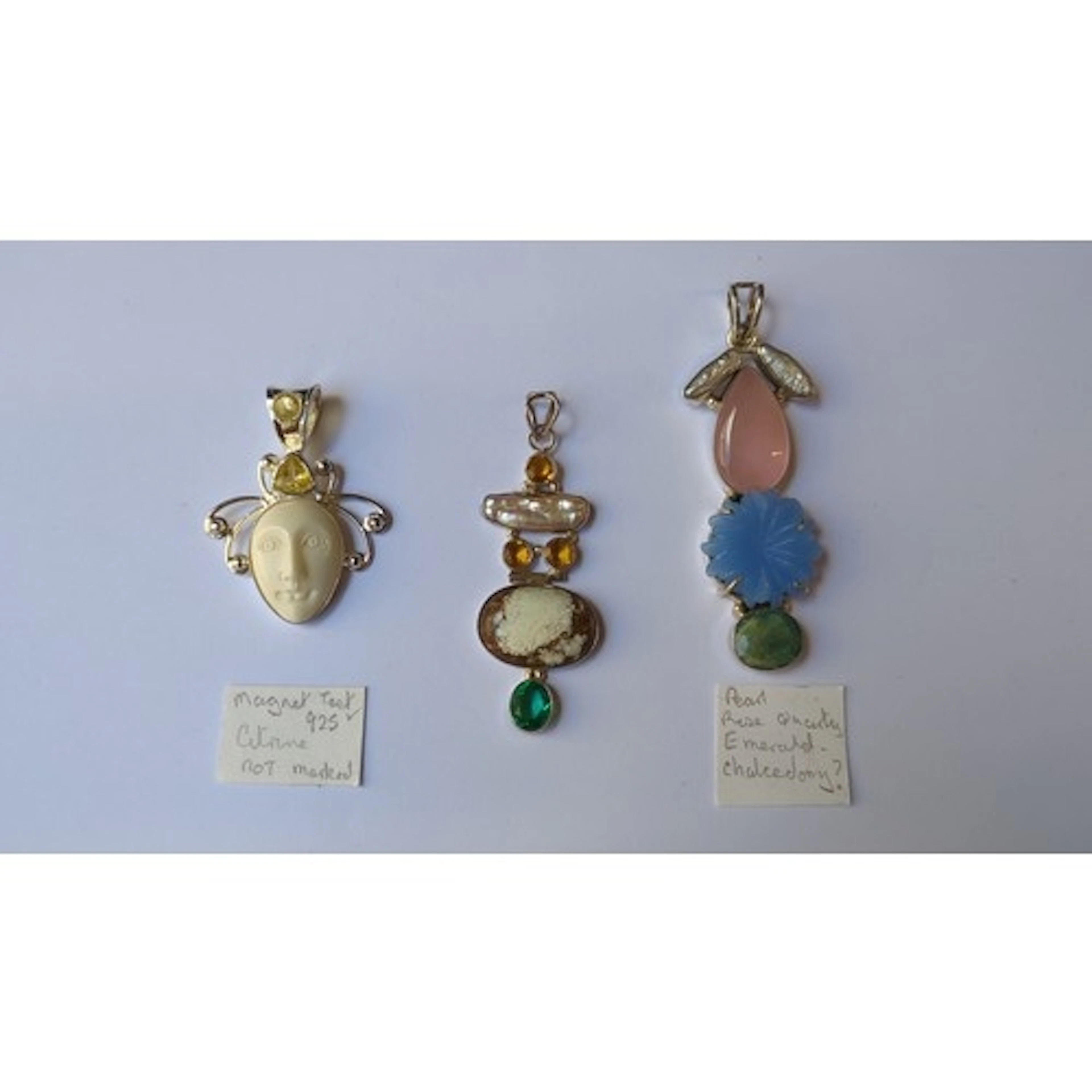 A group of three silver pendants, one with carved mask plaqu...