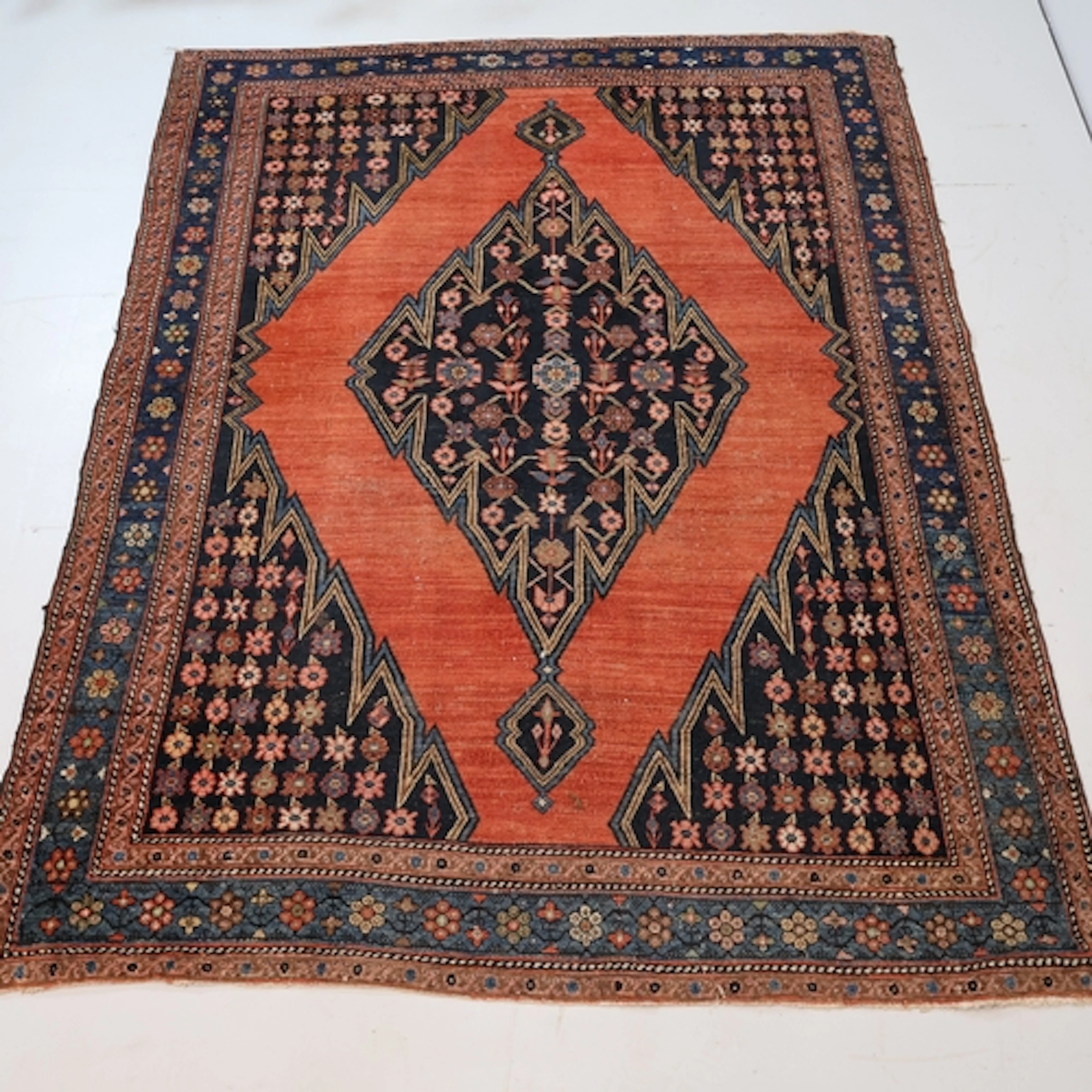 A red and blue ground Persian area rug with floral motifs an...