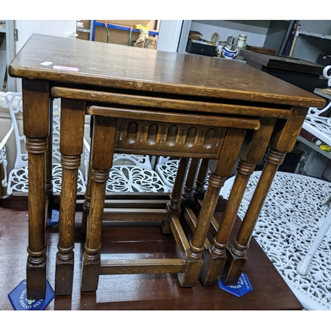 A dark oak nesting set of three tables, turned legs united b...