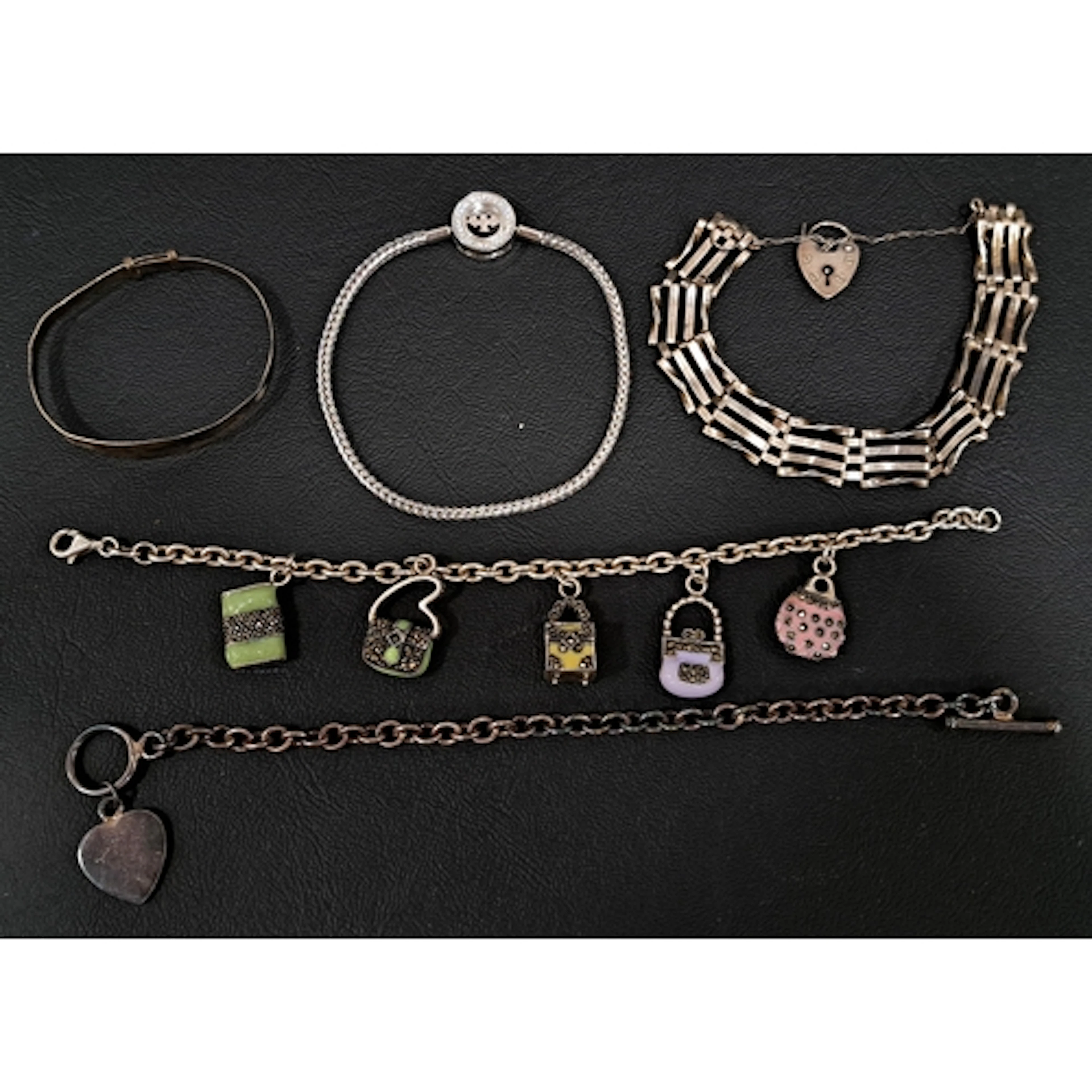 FIVE SILVER BRACELETS comprising a gate bracelet, another wi...