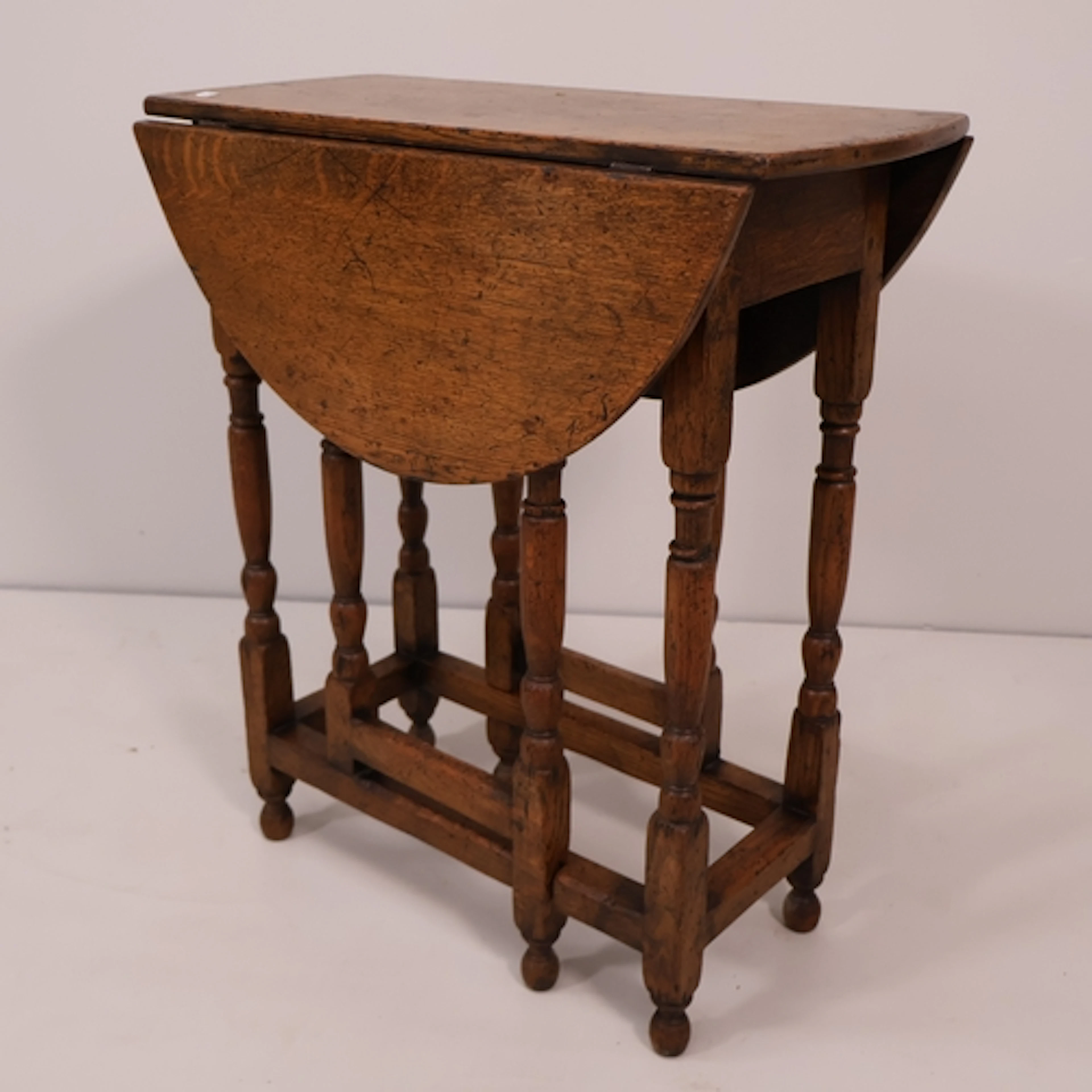 An antique stained oak oval gateleg table. W60cm, H66cm, D30...