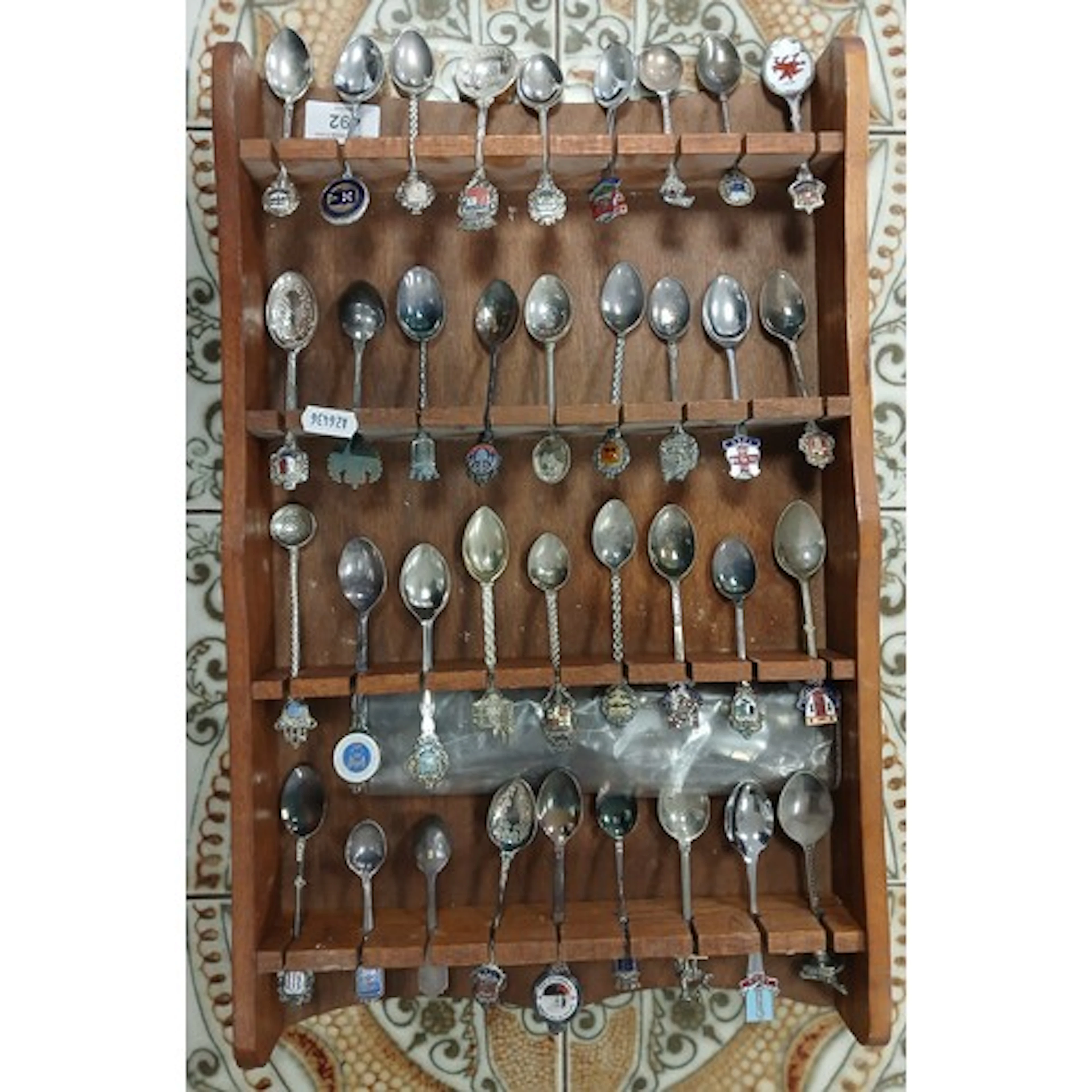 Collection of souvenir spoons on a wall rack.