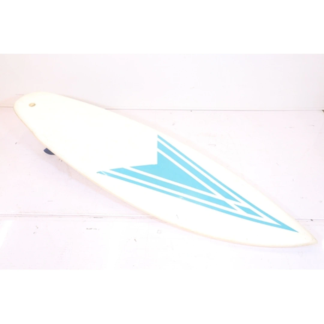 Surfboard having teal/blue geometric arrow design on a white...