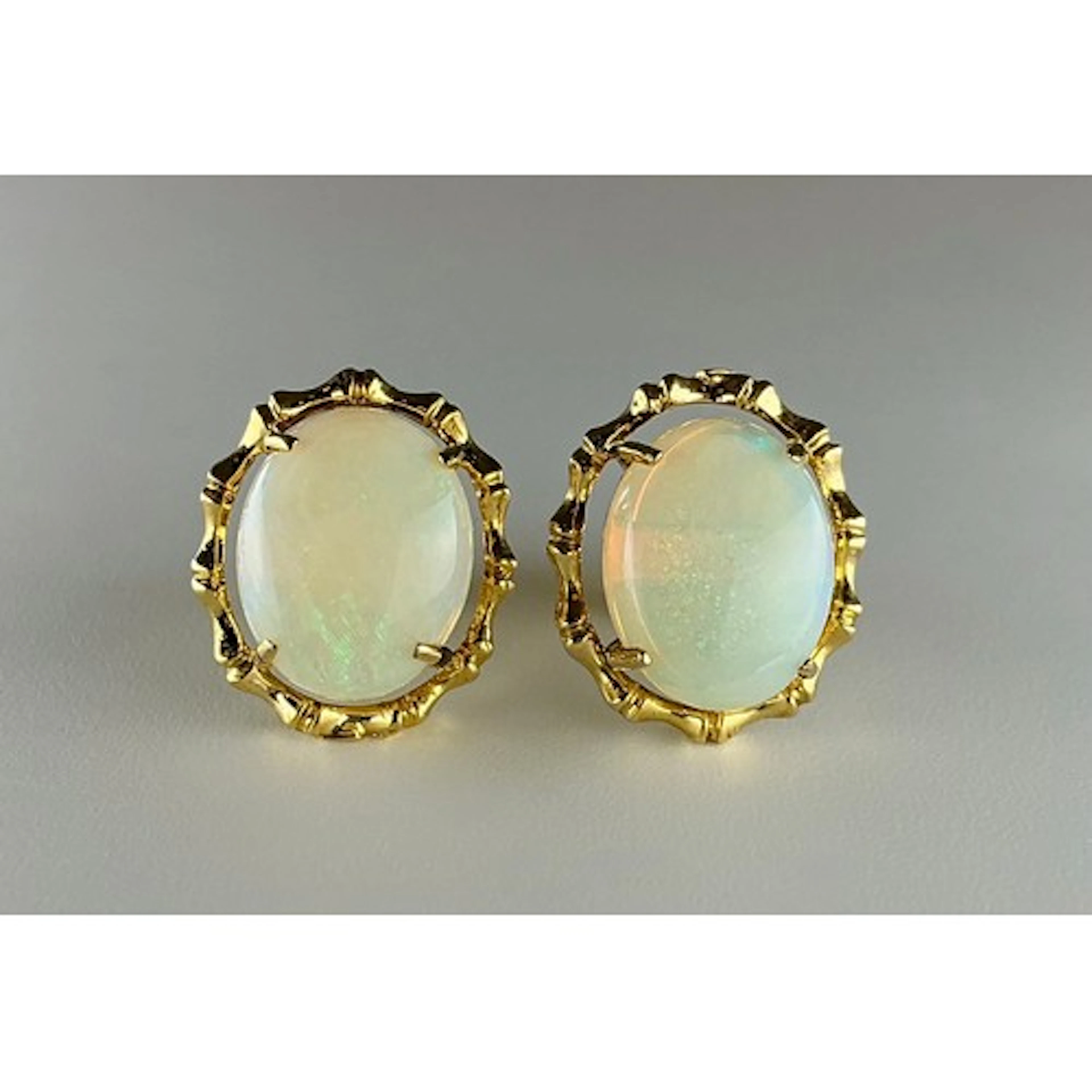 A pair of opal earrings, oval cabochon opals with orange gre...