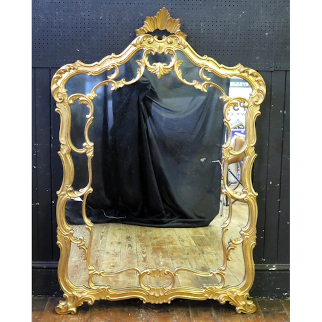 A large giltwood wall mirror, of arched outline, with foliat...